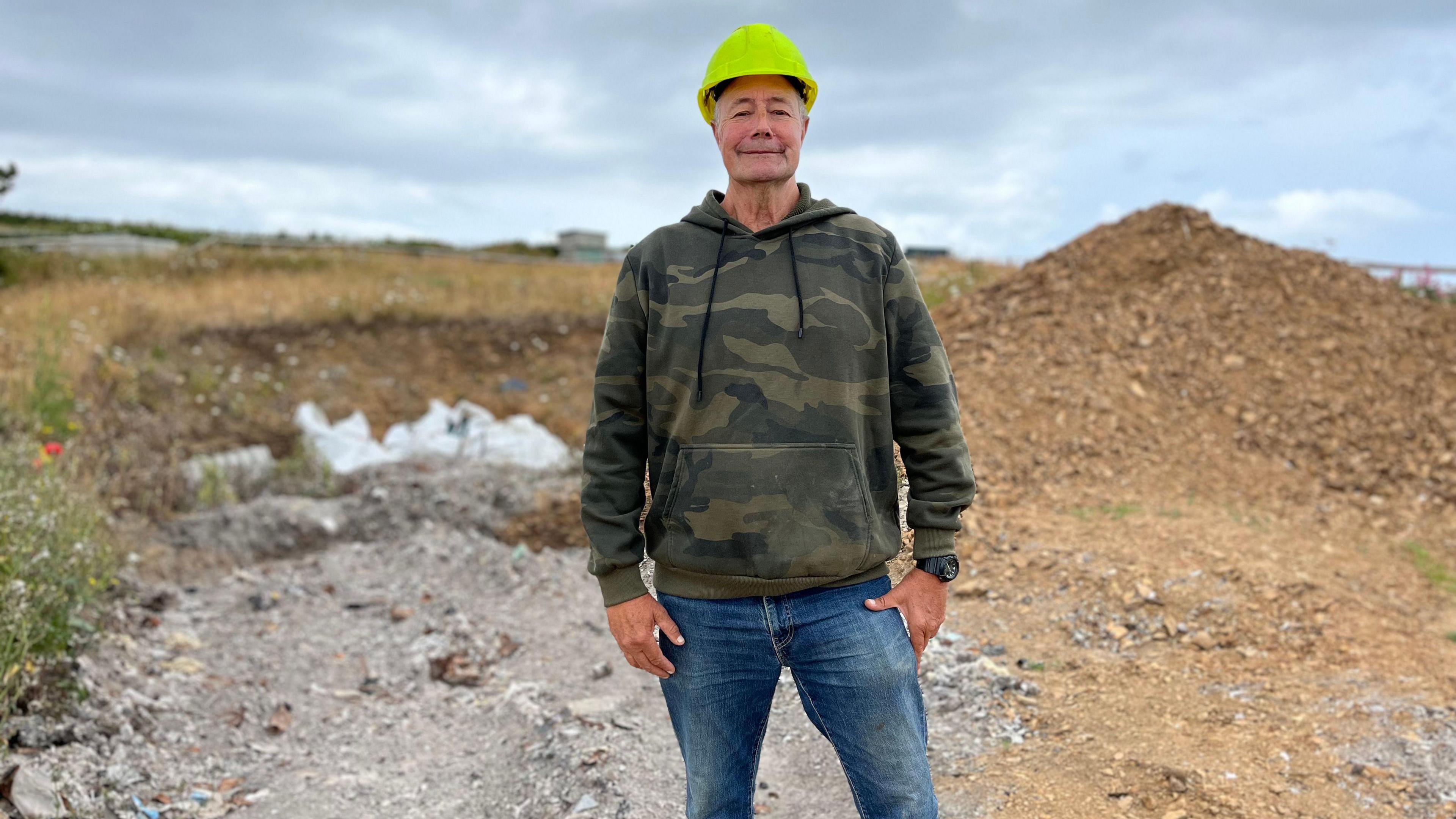 Conseiller Frank Makepeace stood in front of the ash of burnt rubbish