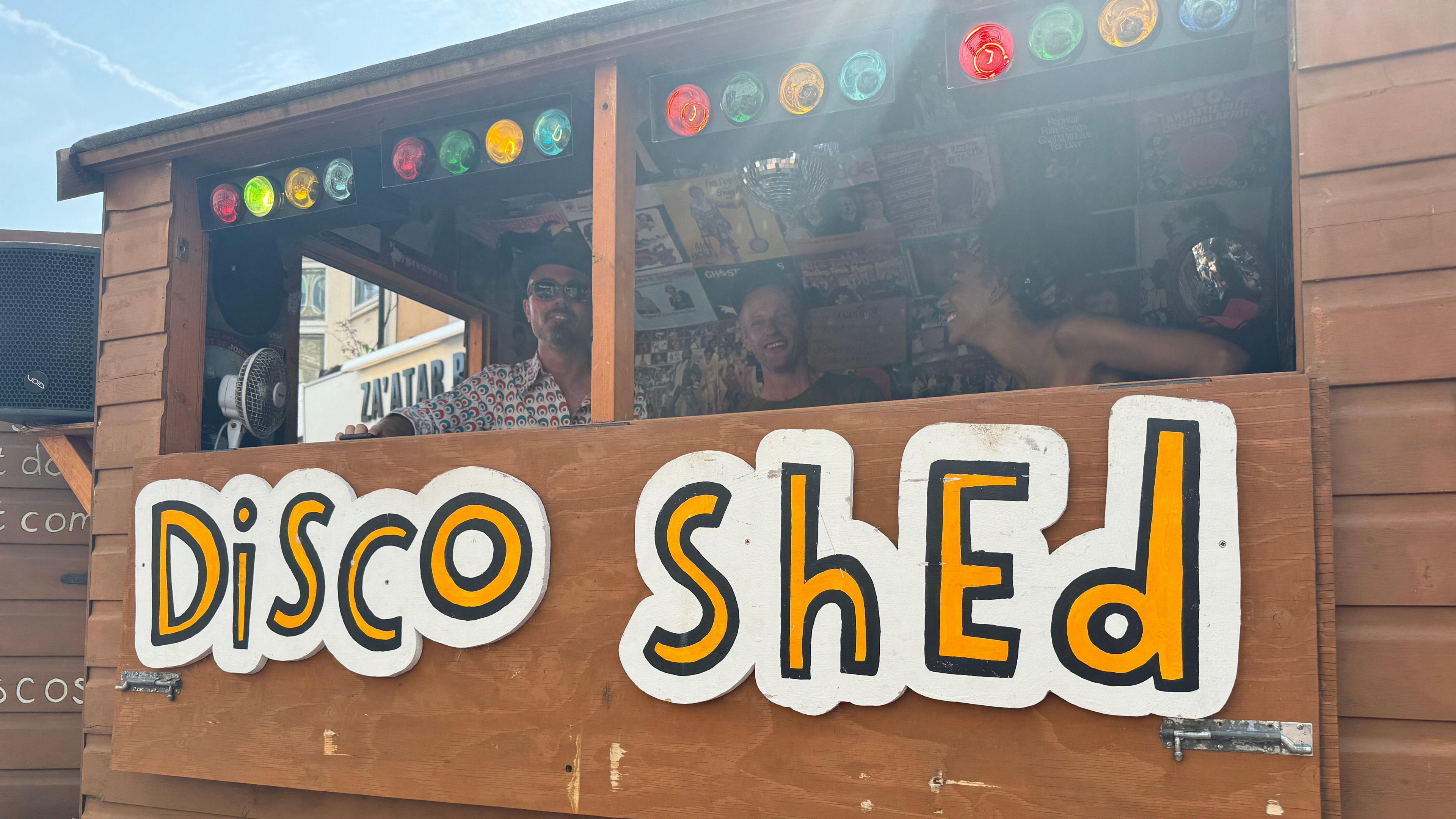 A shed playing music, with the sign disco shed on the front of it.