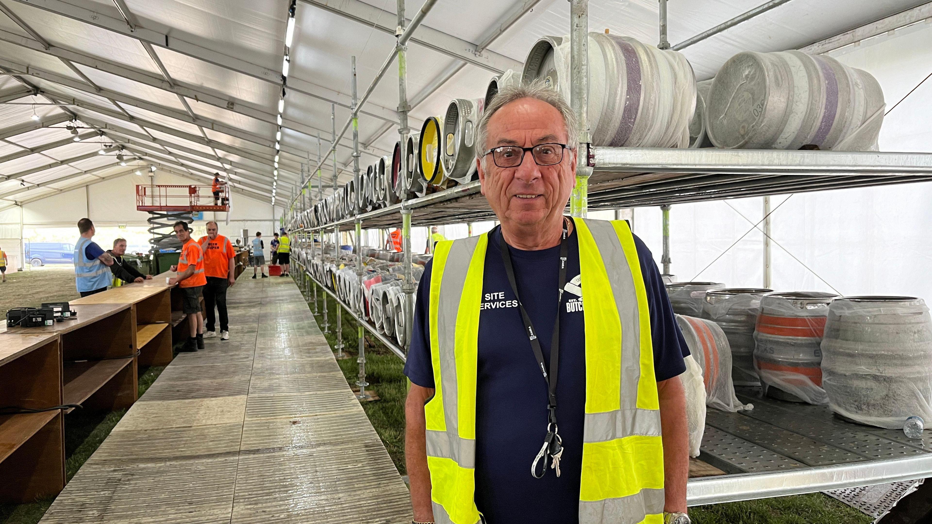 Mike Lane wearing a hi-vis jacket standing in front of metal barrels of beer 