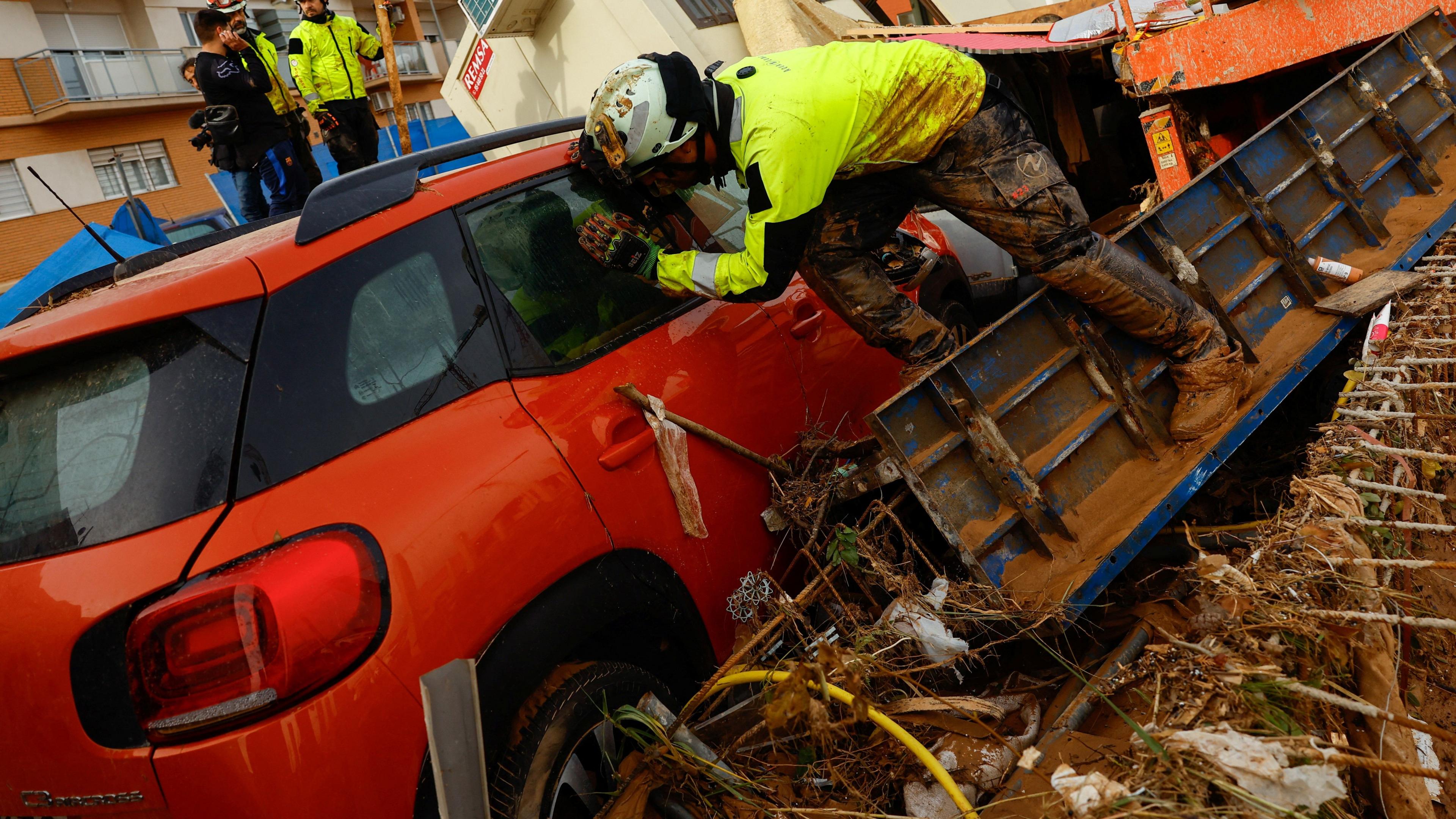 A firefighter looks inside a car 