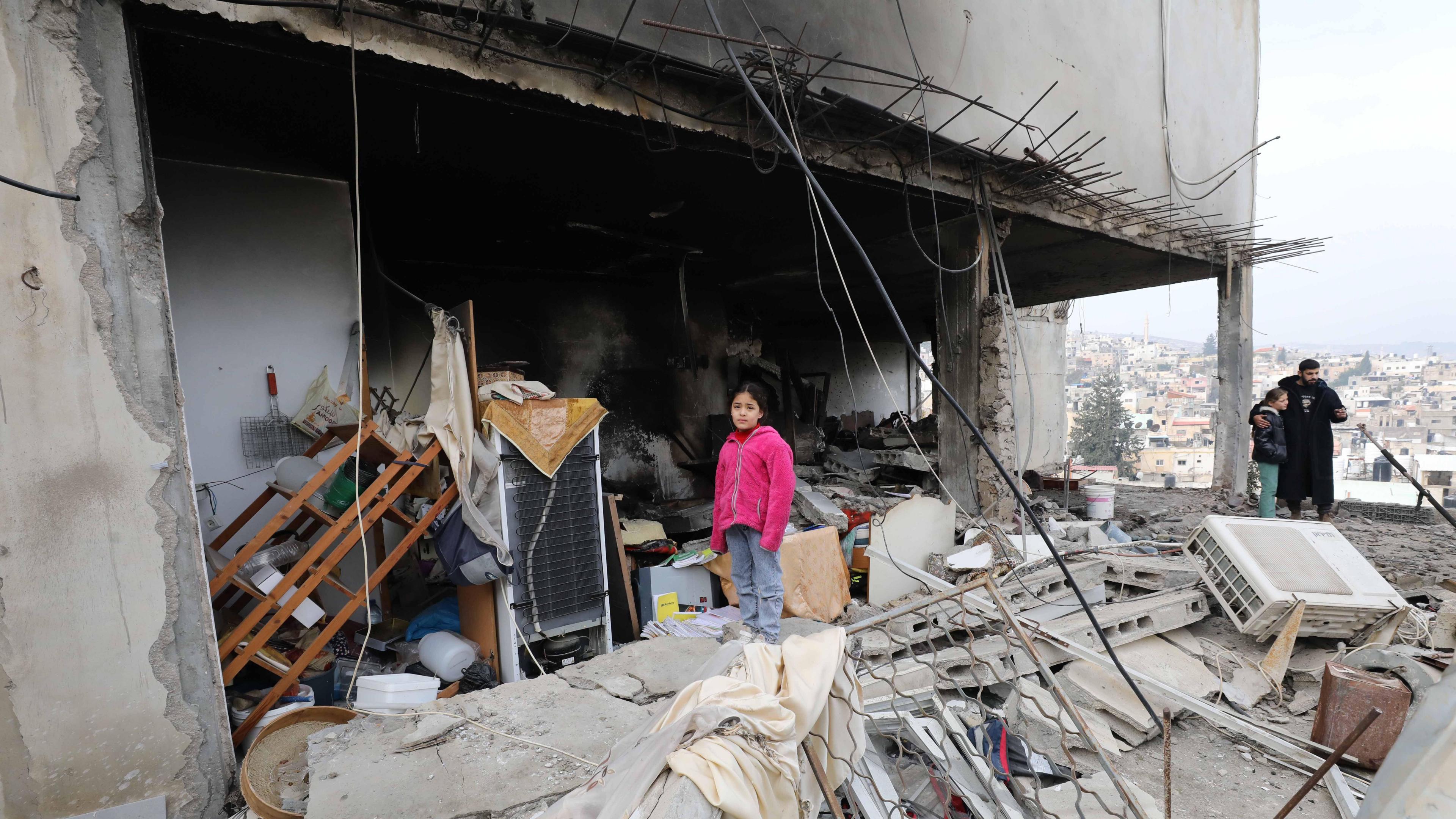 Palestinian residents inspect the area among the rubble of damaged buildings