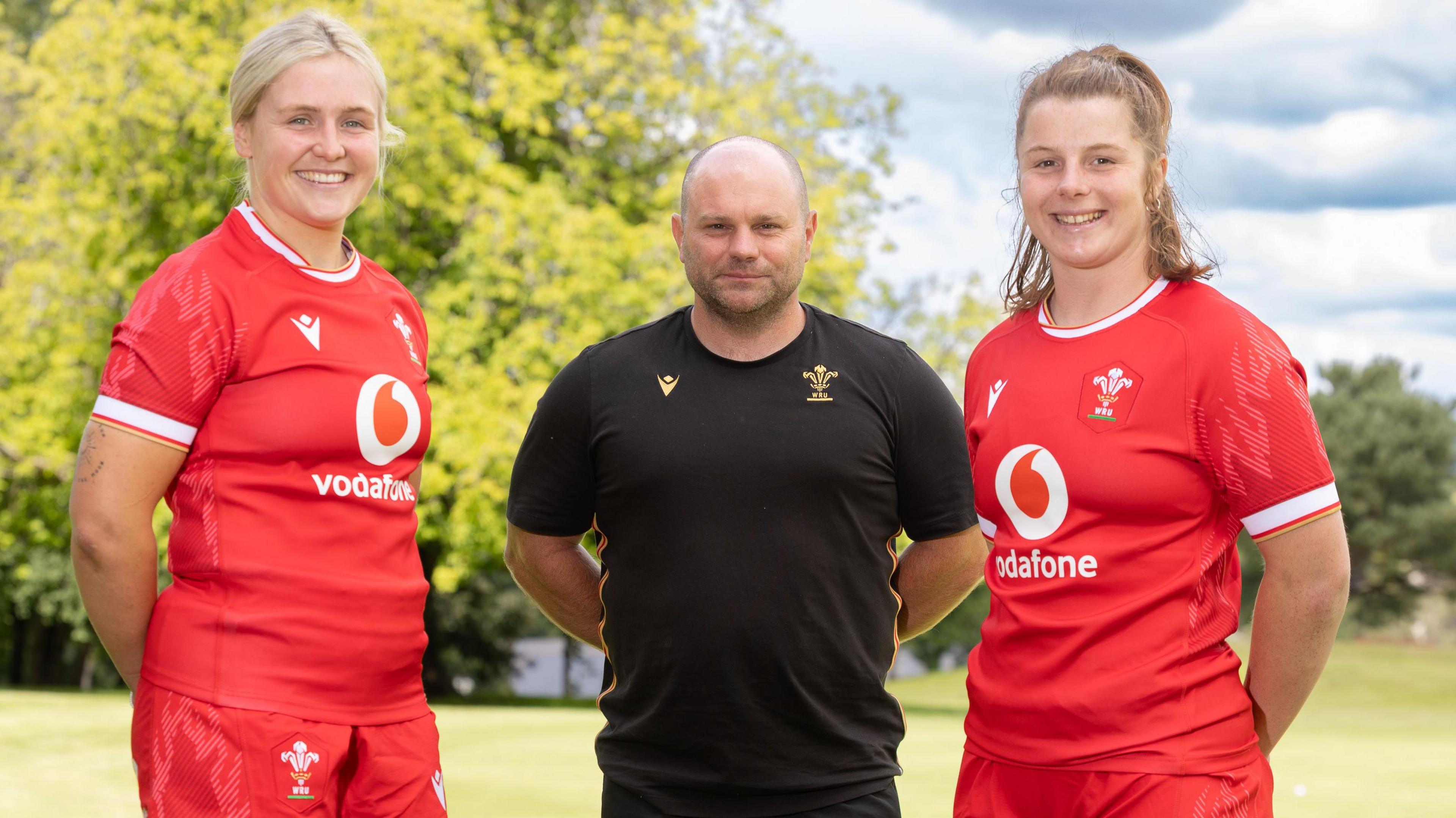 Alex Callender and Kate Williams in Wales kits stood either side of coach Sean Lynn in black training kit