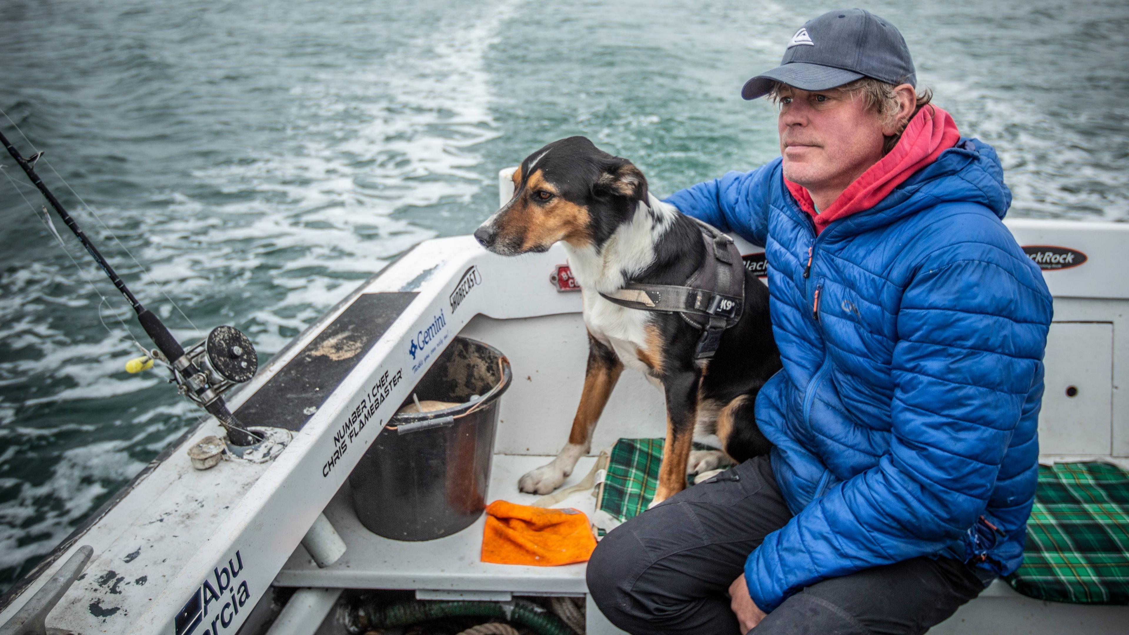 Y ffotograffydd Iolo Penri a'i gi, Mos, yn pysgota ar gwch Gari