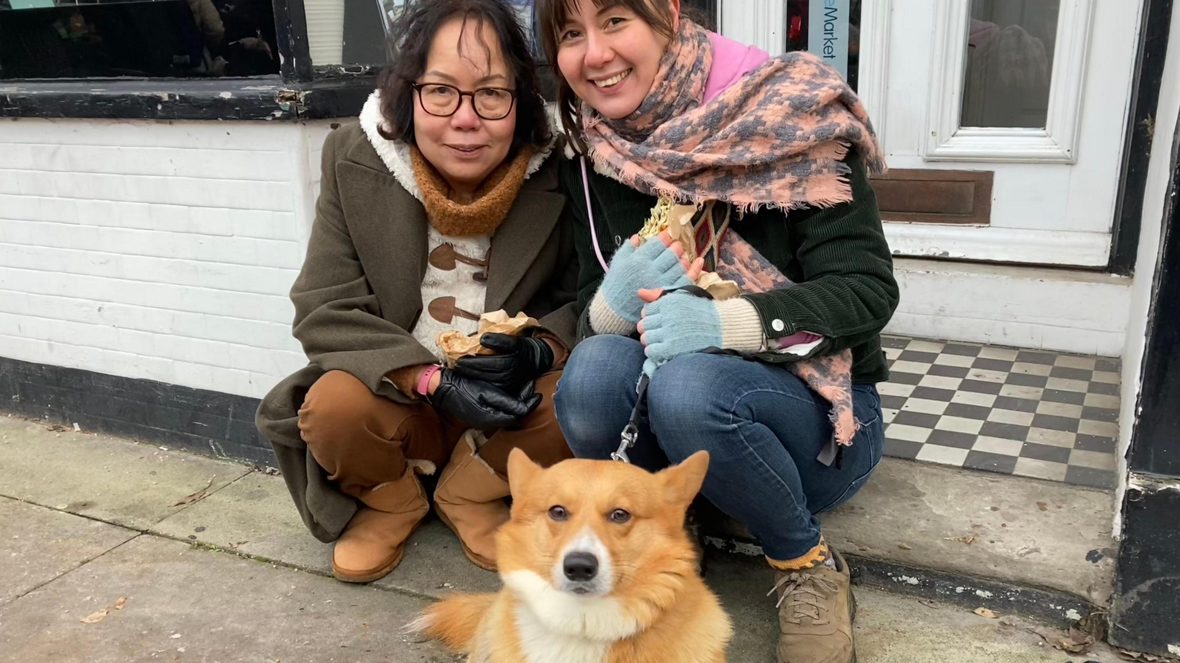 Two women and a corgi dog