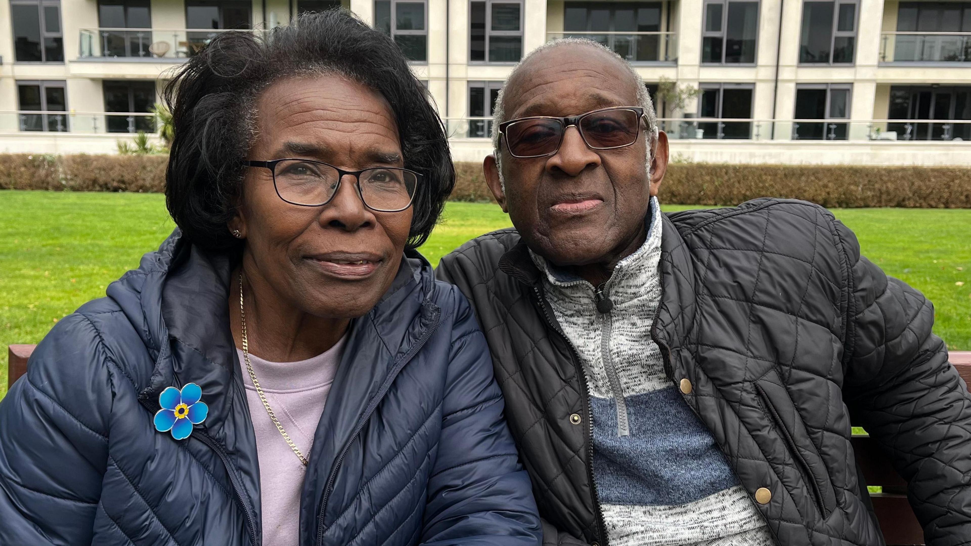 Cynthia and Raymond James sat on a bench wearing coats.