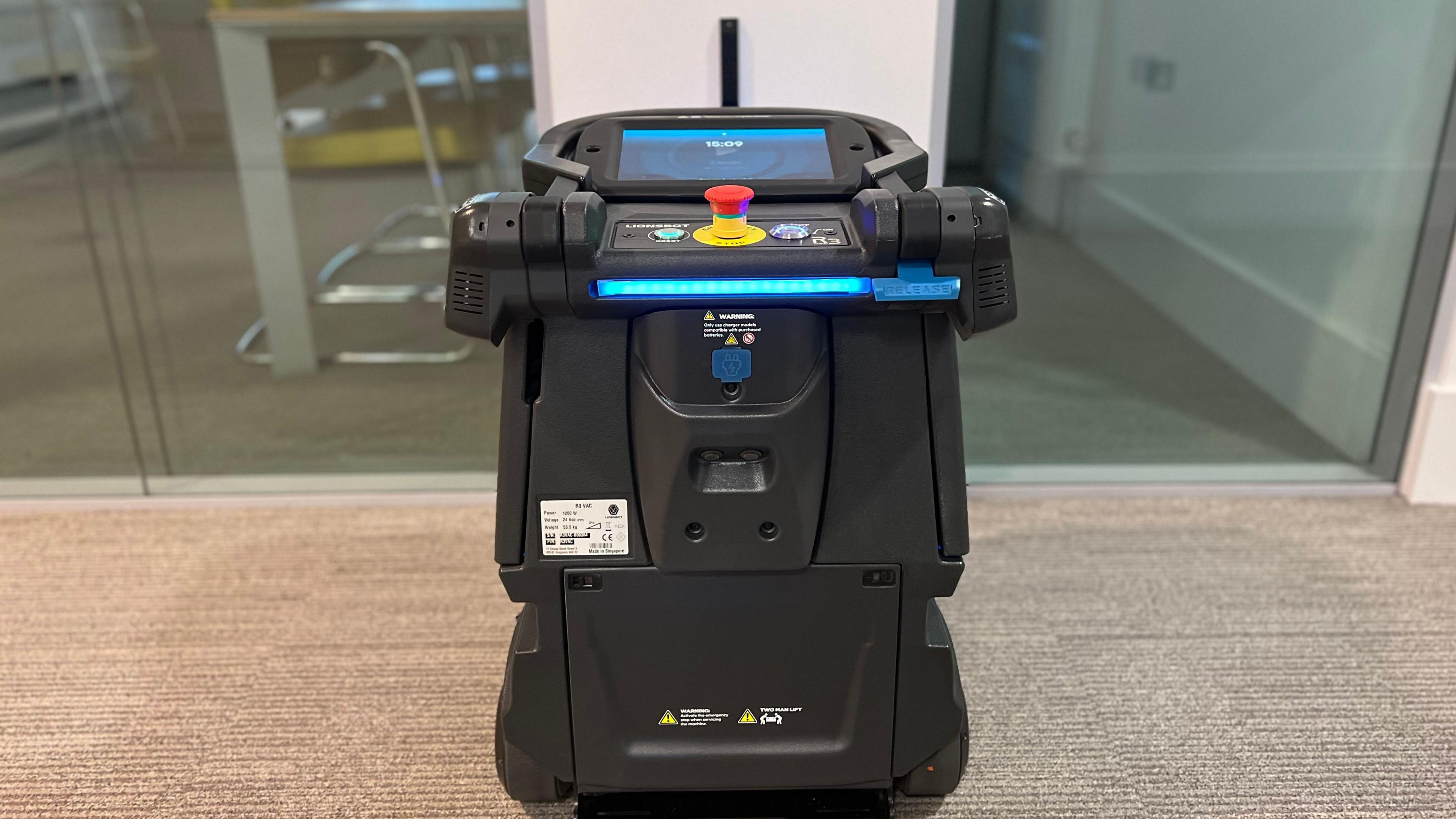 A robot vacuum cleaner, small black machine with a blue screen displaying words 