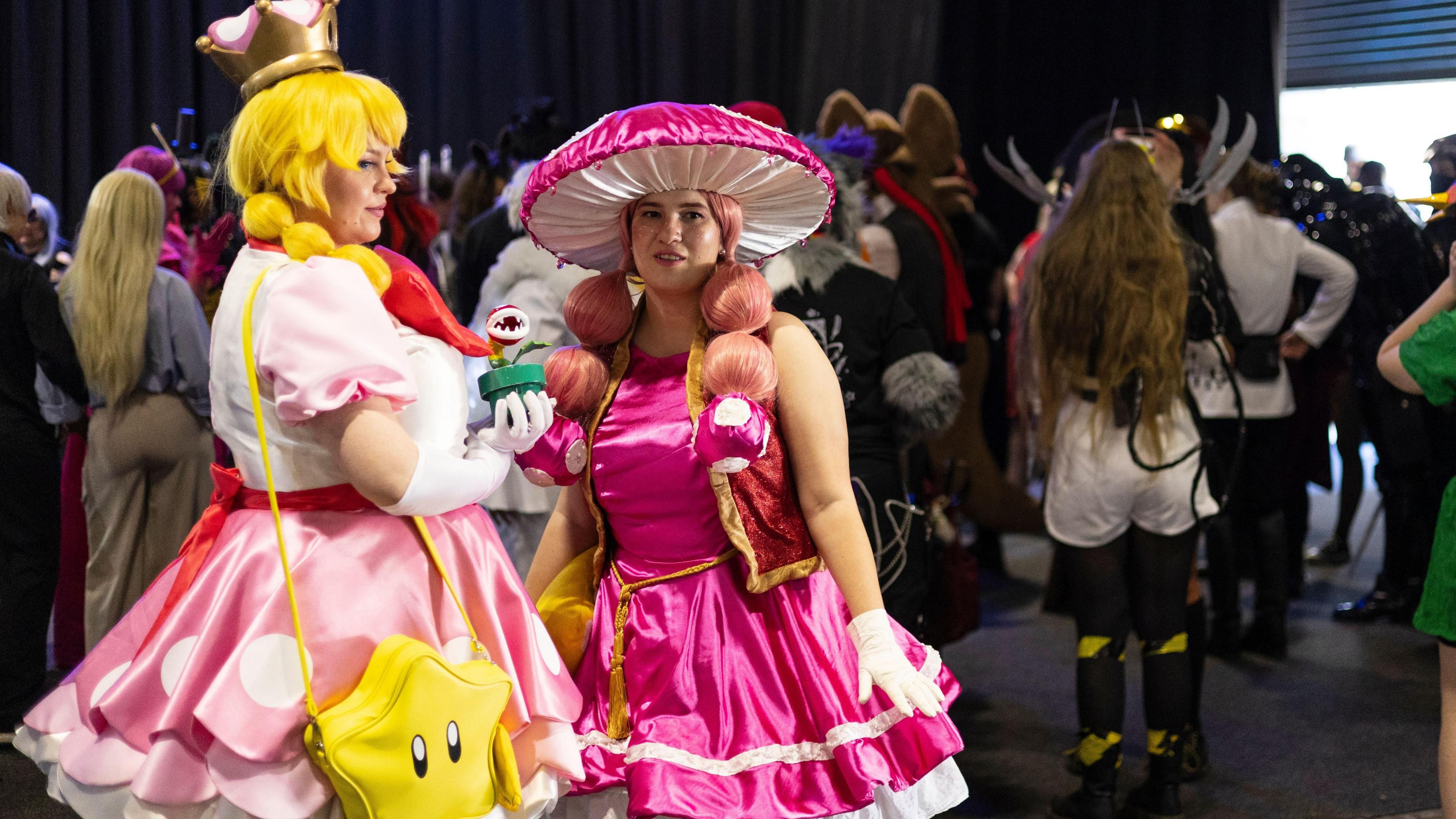 Two people standing wearing elaborate pink fancy dress. They both have on pink wigs. There are other people in fancy dress behind them in Johannesburg, South Africa - Thursday 28 August 2025
