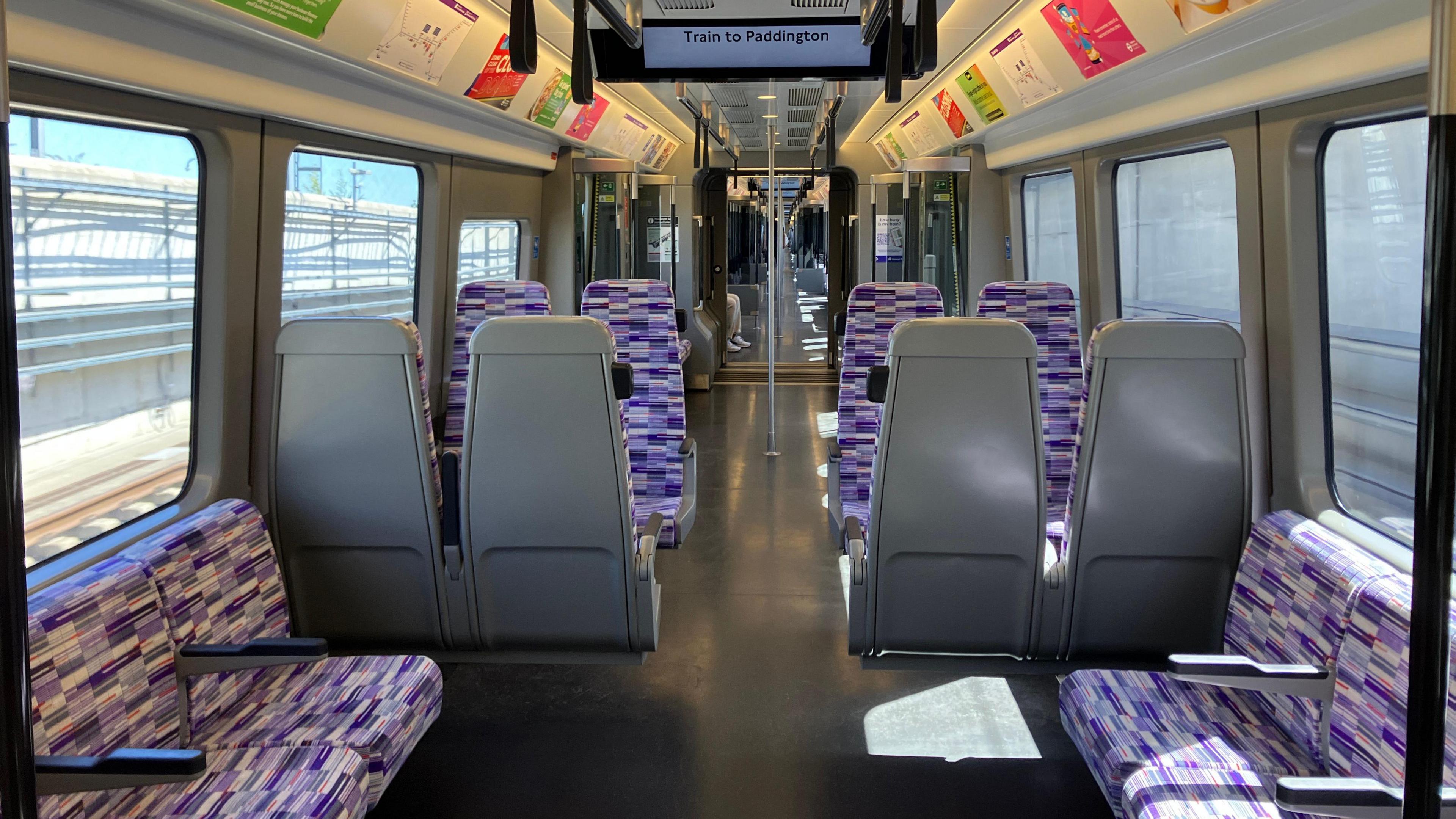 Purple seats inside an Elizabeth line carriage with no passengers on a sunny day