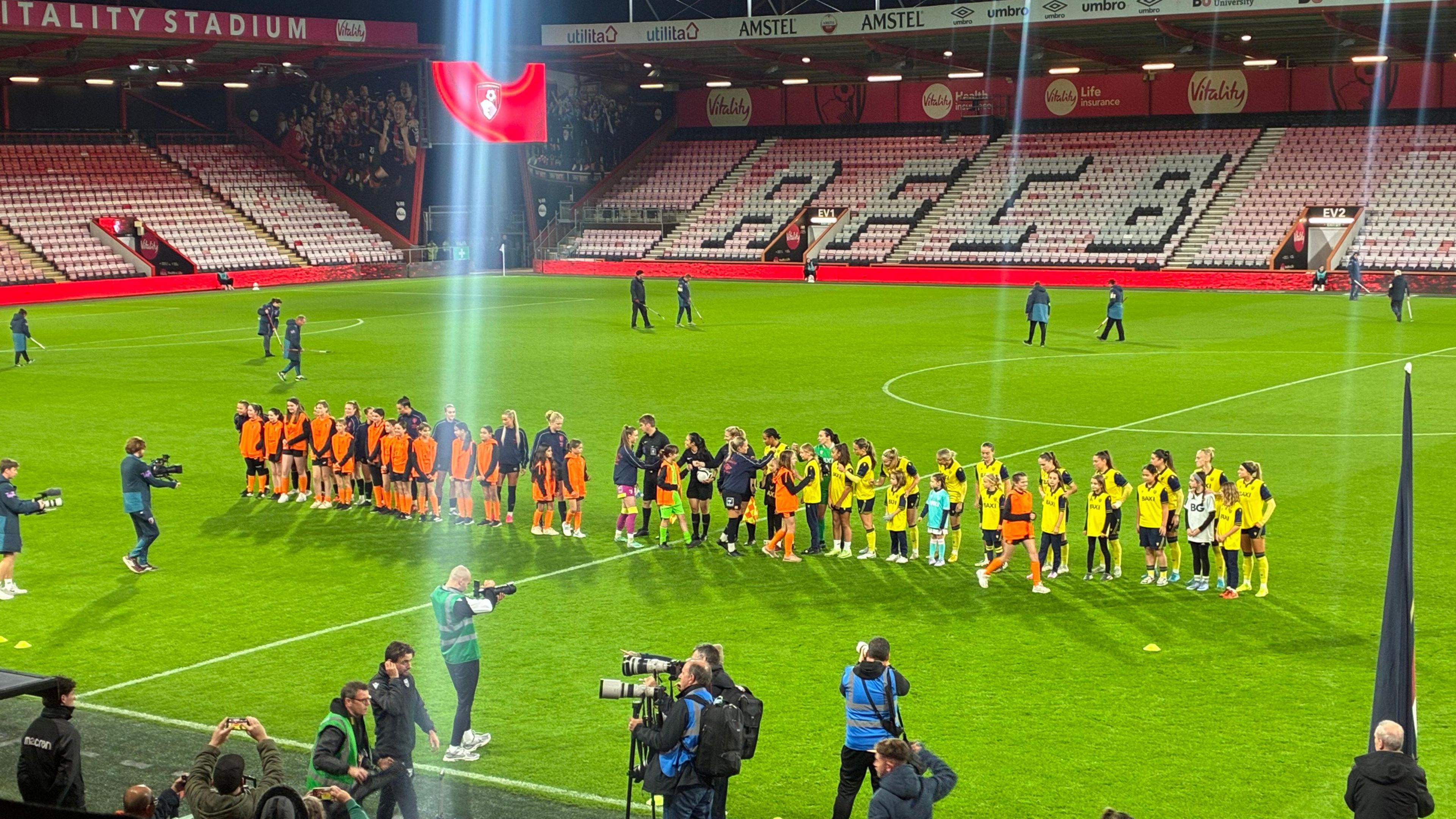 AFC Bournemouth Women and Oxford United Women line up to shake hands on the pitch at the Vitality stadium.
