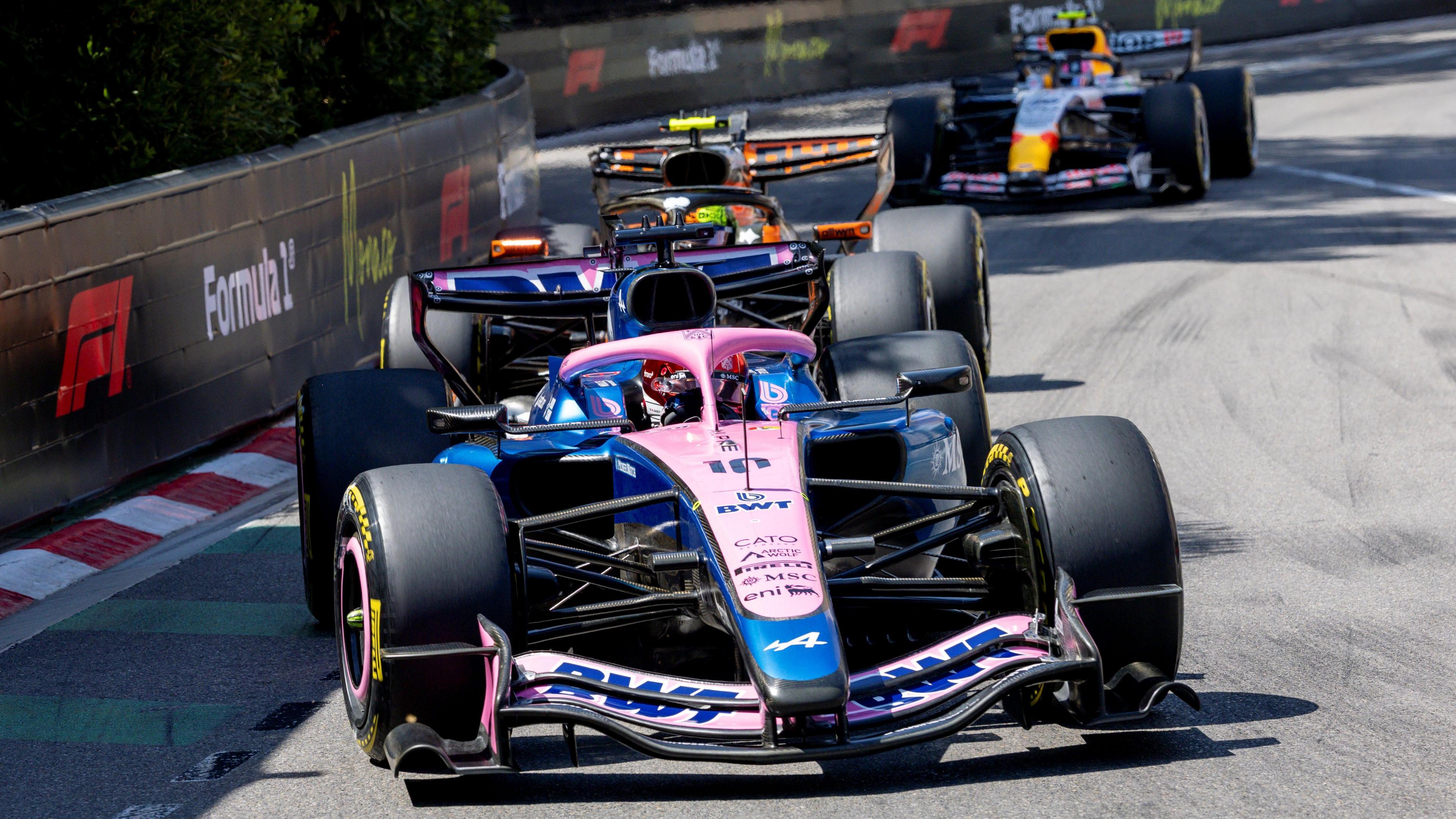 Alpine's Pierre Gasly with McLaren's Lando Norris right behind him, and a Racing Bulls in the background, approaching the hairpin during the Monaco Grand Prix