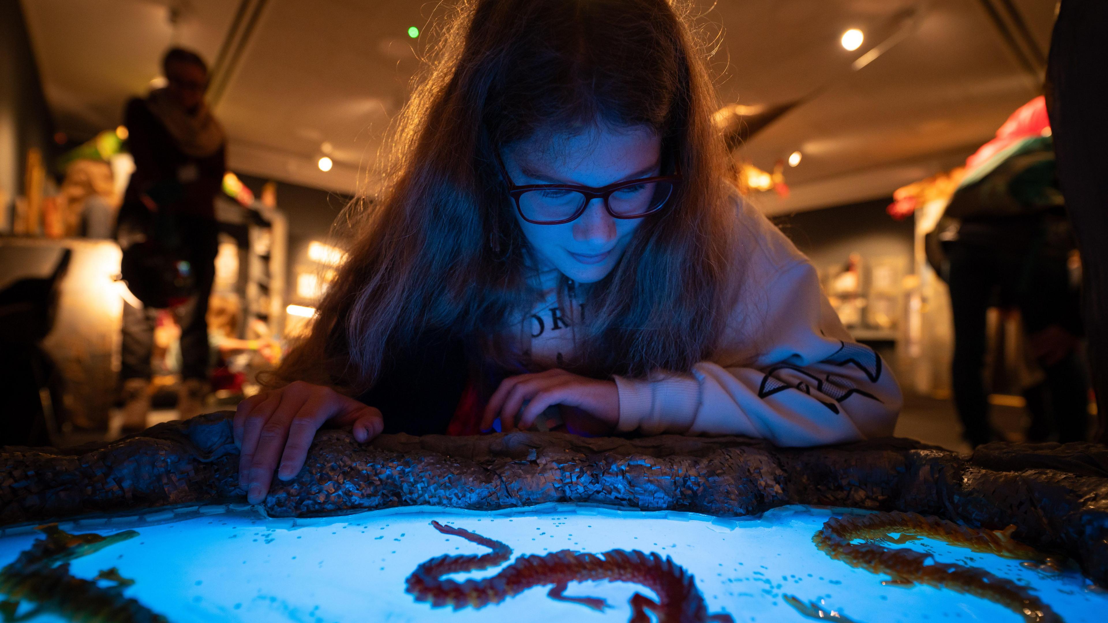 A teenage girl looks down at a blue game.