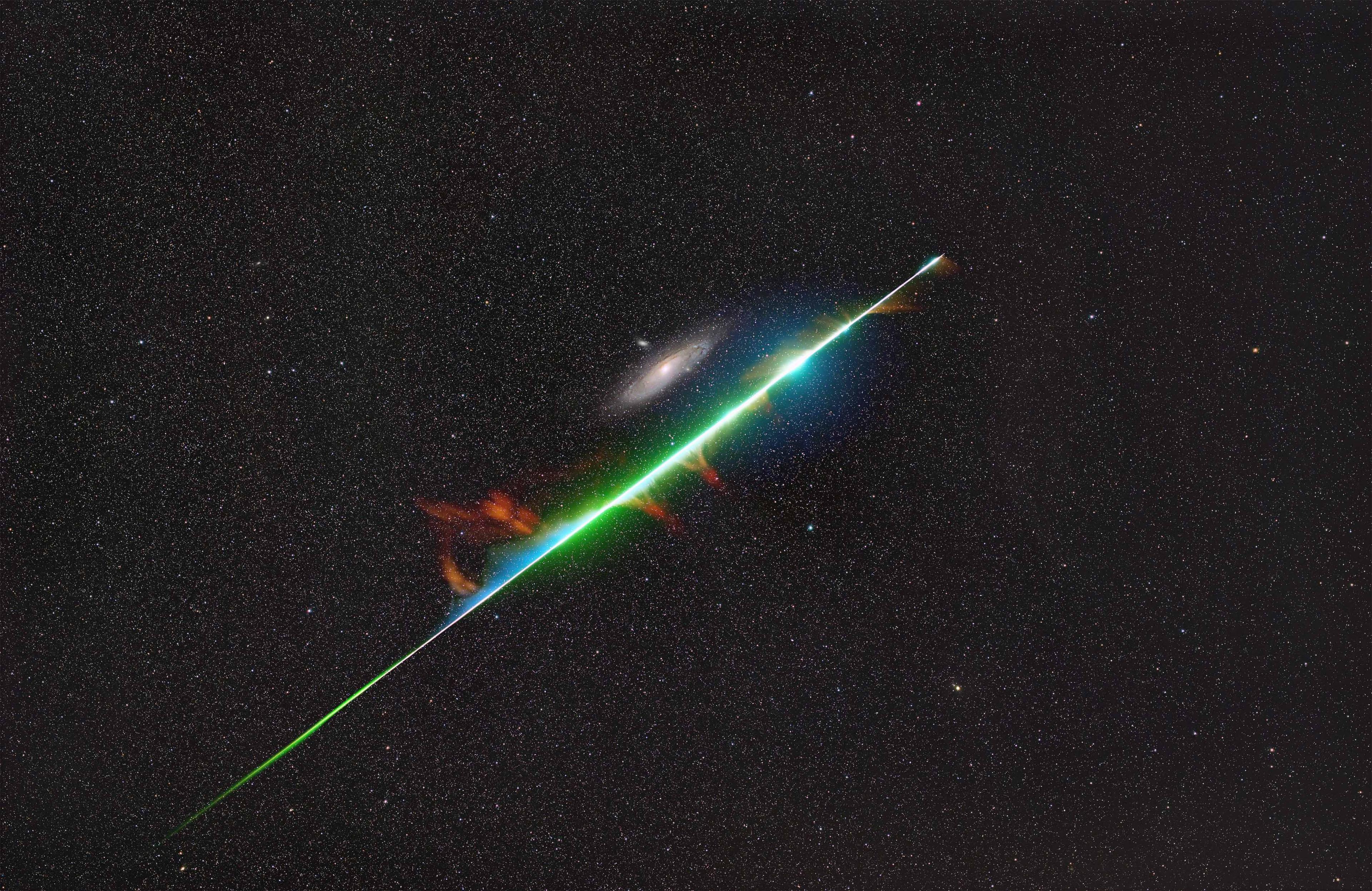 This photograph captures a serendipitous moment when a brilliant fireball from the Perseid meteor shower appeared to graze M31, the Andromeda Galaxy.