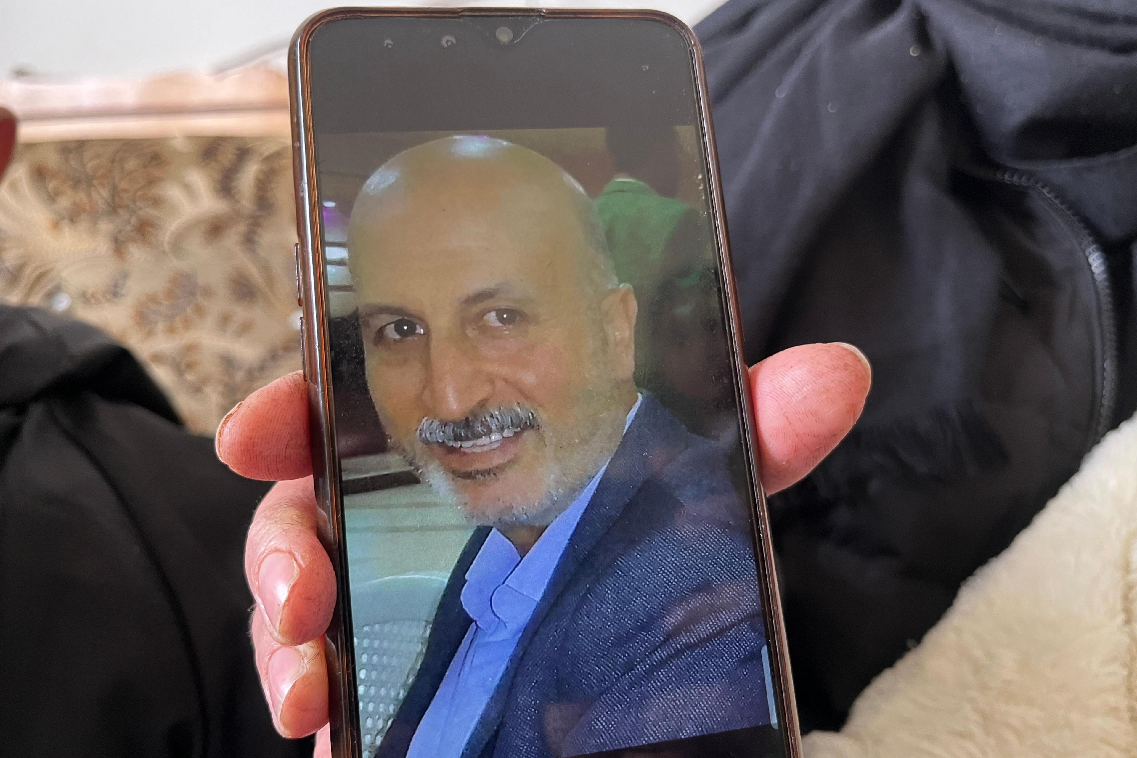 A photo of a bald man with a moustache is seen on a mobile phone screen