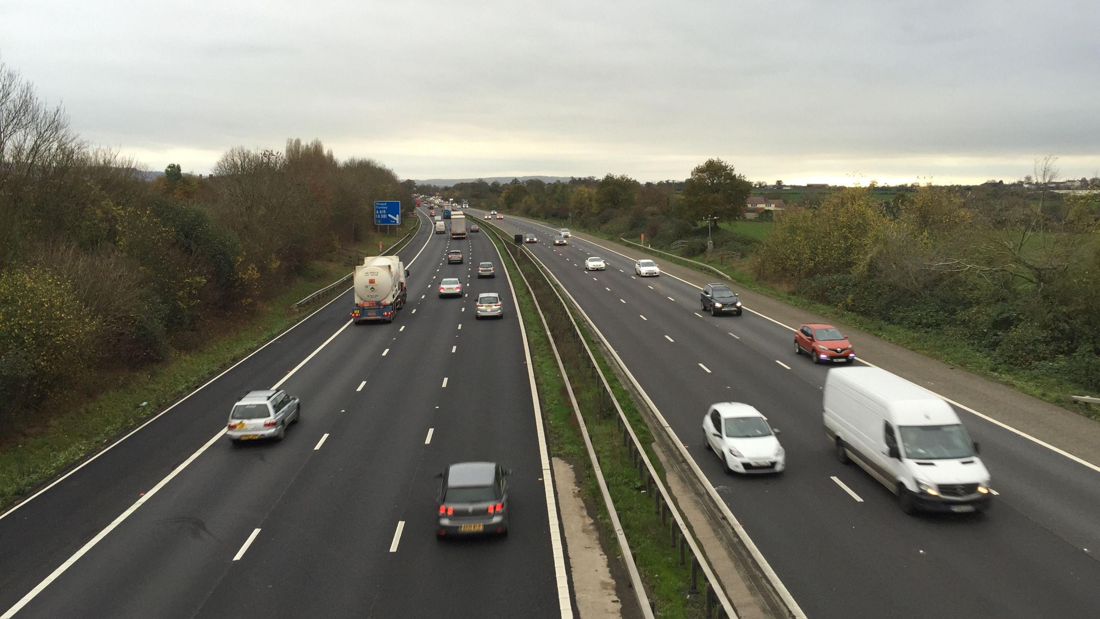 A photo showing both sides of a motorway, with traffic travelling along three lanes on both sides.