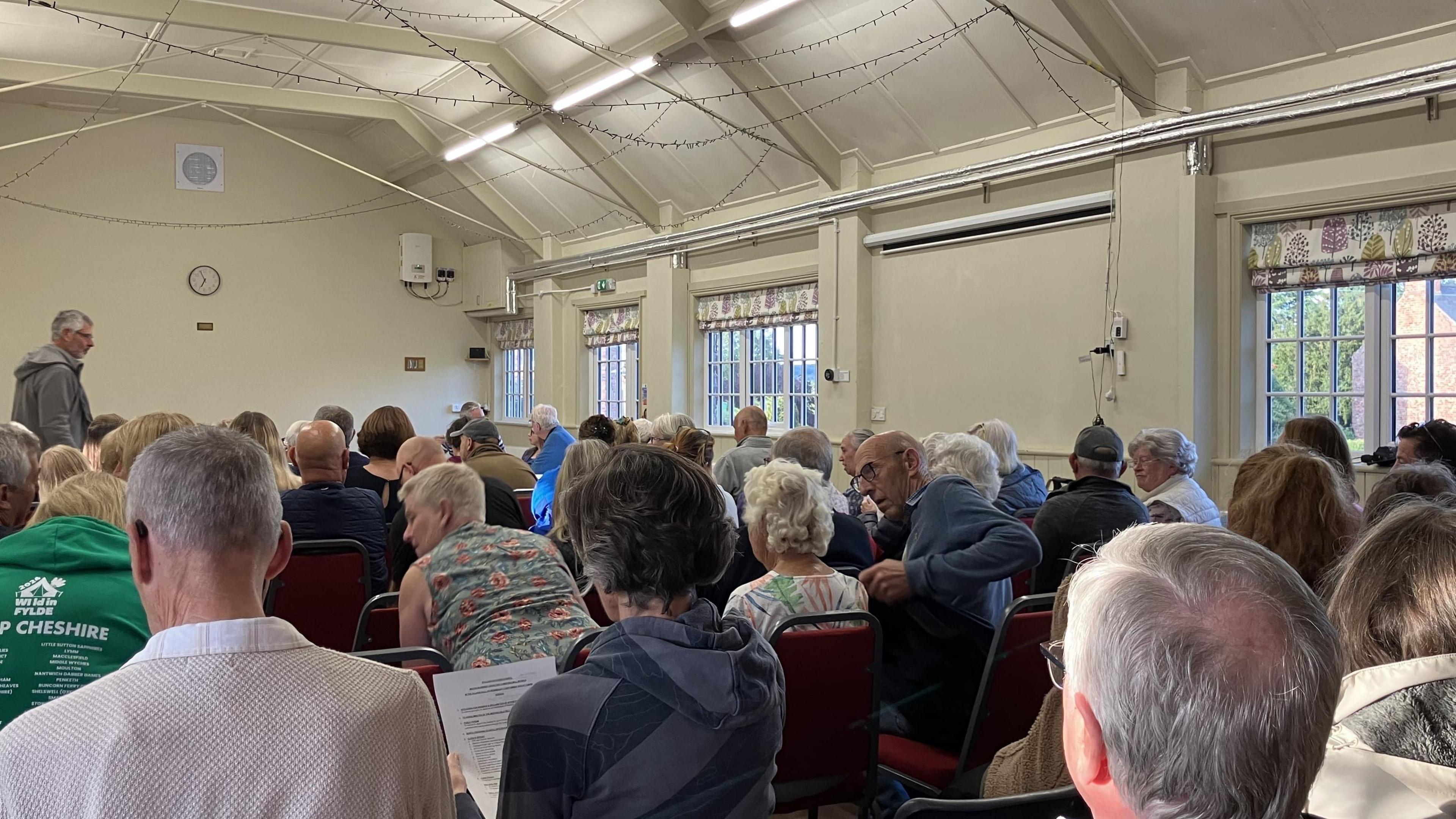 A village hall full of people waiting for a meeting to start. 