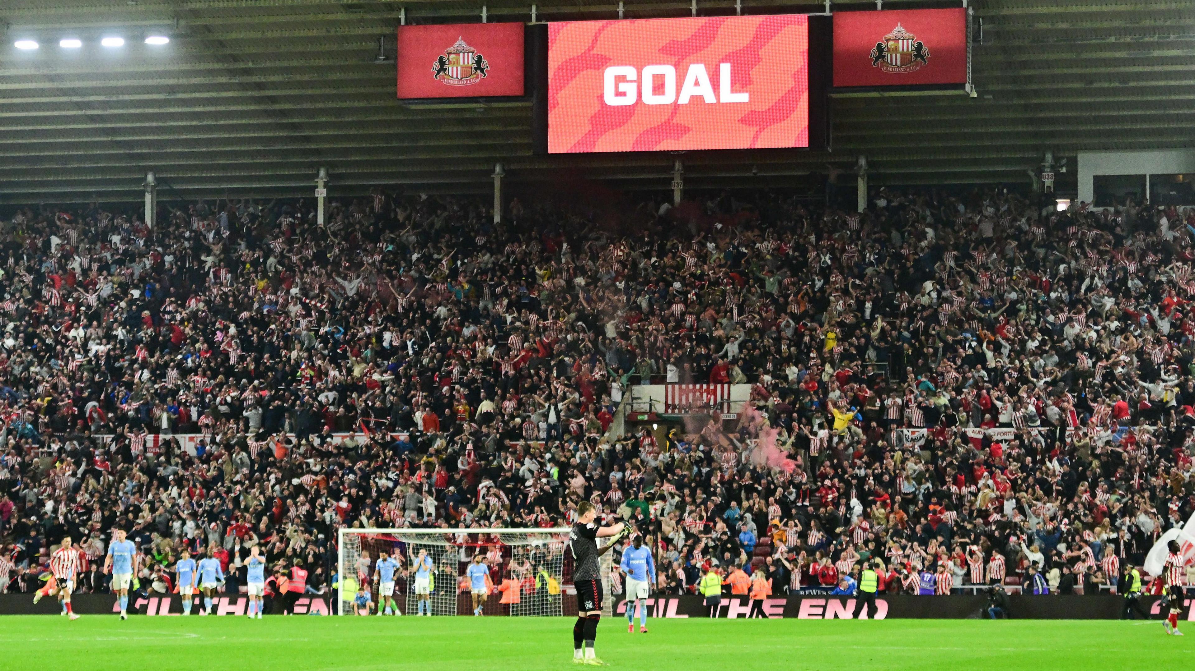 Sunderland players celebrate their last minute equaliser against Coventry with the stadium scoreboard showing 'Goal'