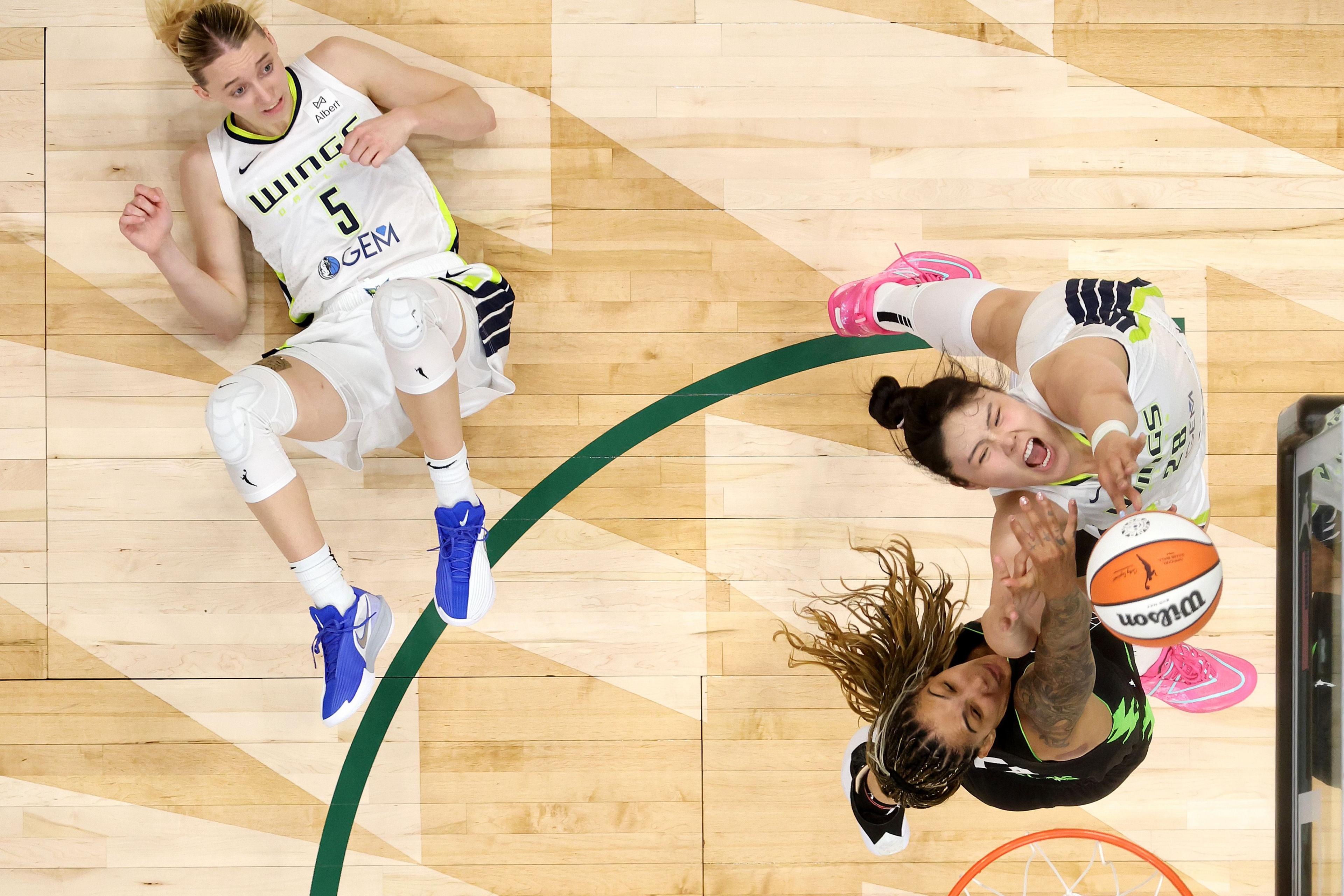Dallas Wings' Paige Bueckers looks on as Seattle Storm's Gabby Williams and team-mate Li Yueru battle for the rebound at Climate Pledge Arena in Seattle, Washington. Photo by Steph Chambers