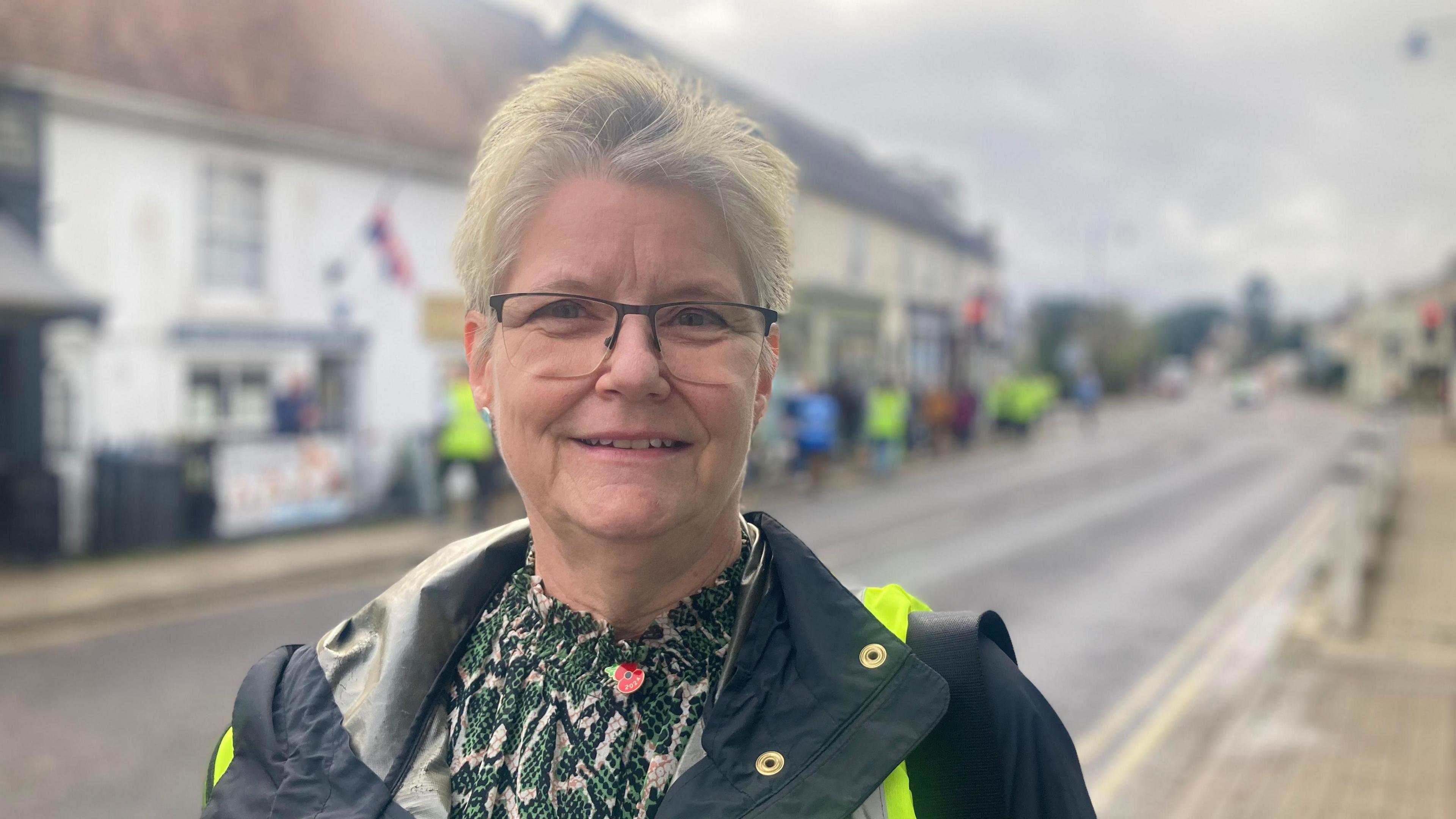 Charlotte Fox wearing a green and cream top and a blue coat