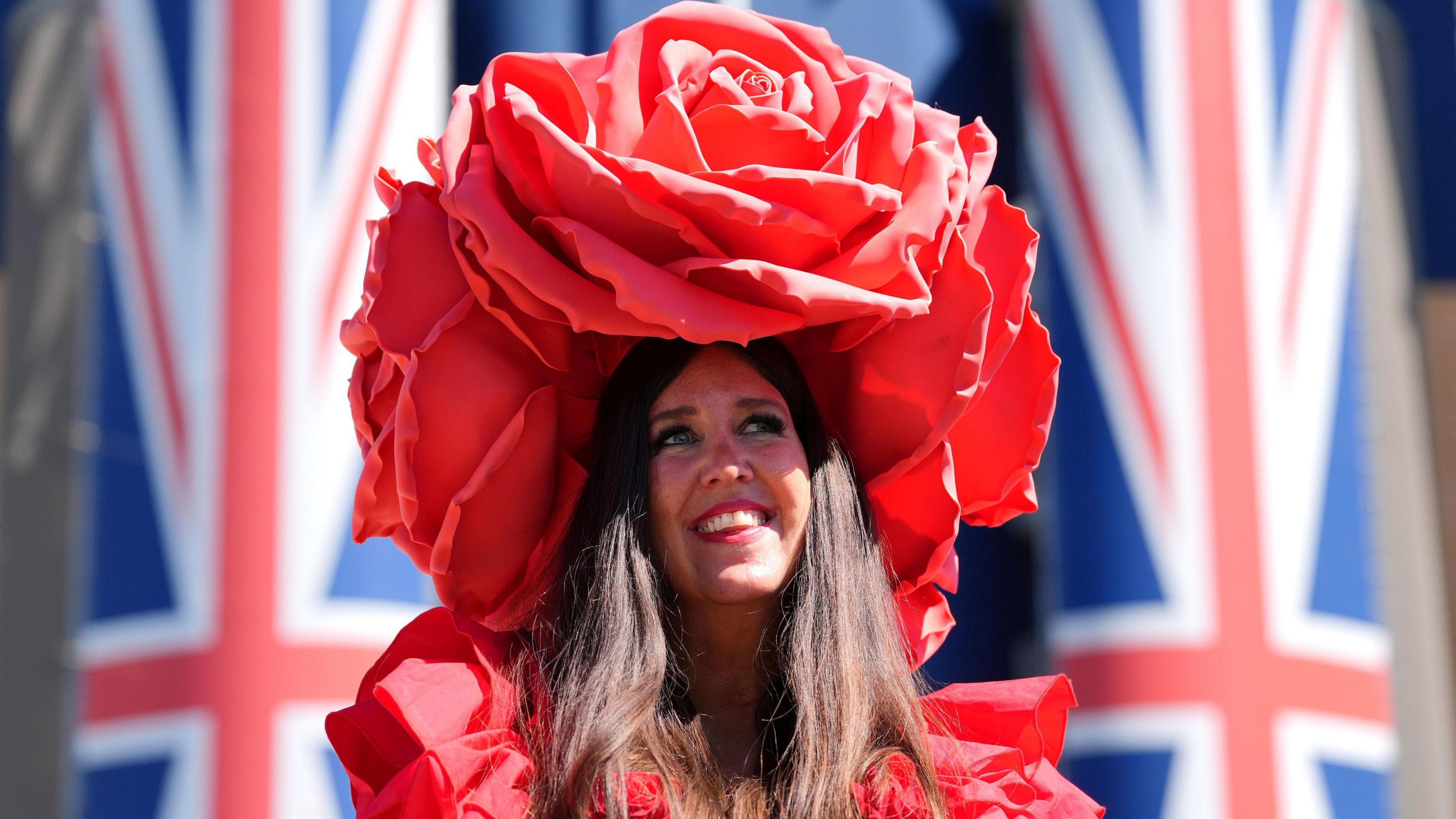 Gemma Mattison, a white woman with long brown hair, wears a large red rose hat