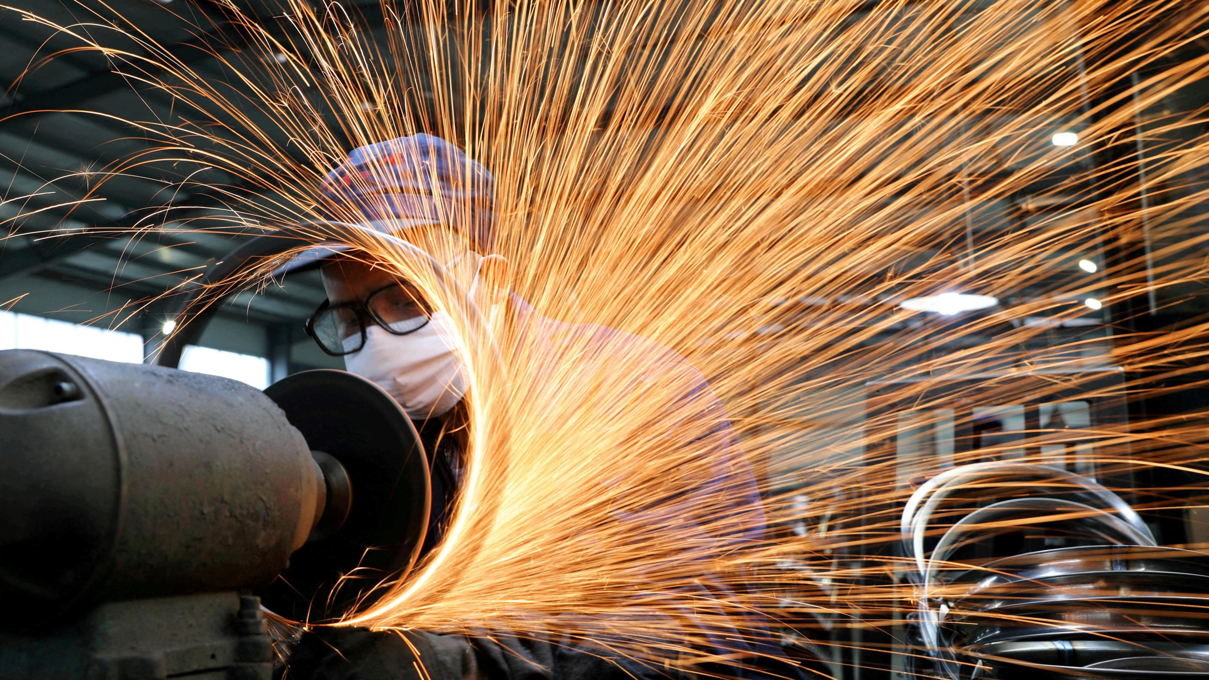 A worker wearing a face mask works on a production line manufacturing bicycle steel rim at a factory in Hangzhou, Zhejiang, China. 