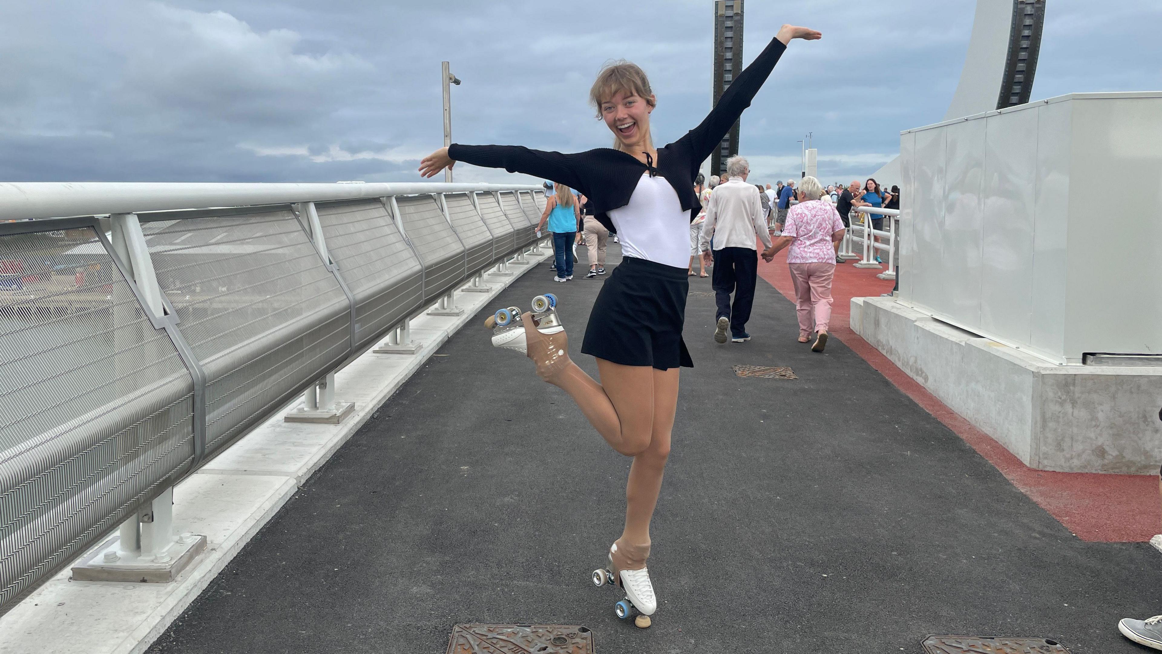 Ellen Siegert posing on the Gull Wing bridge with her arms in the air and one leg raised