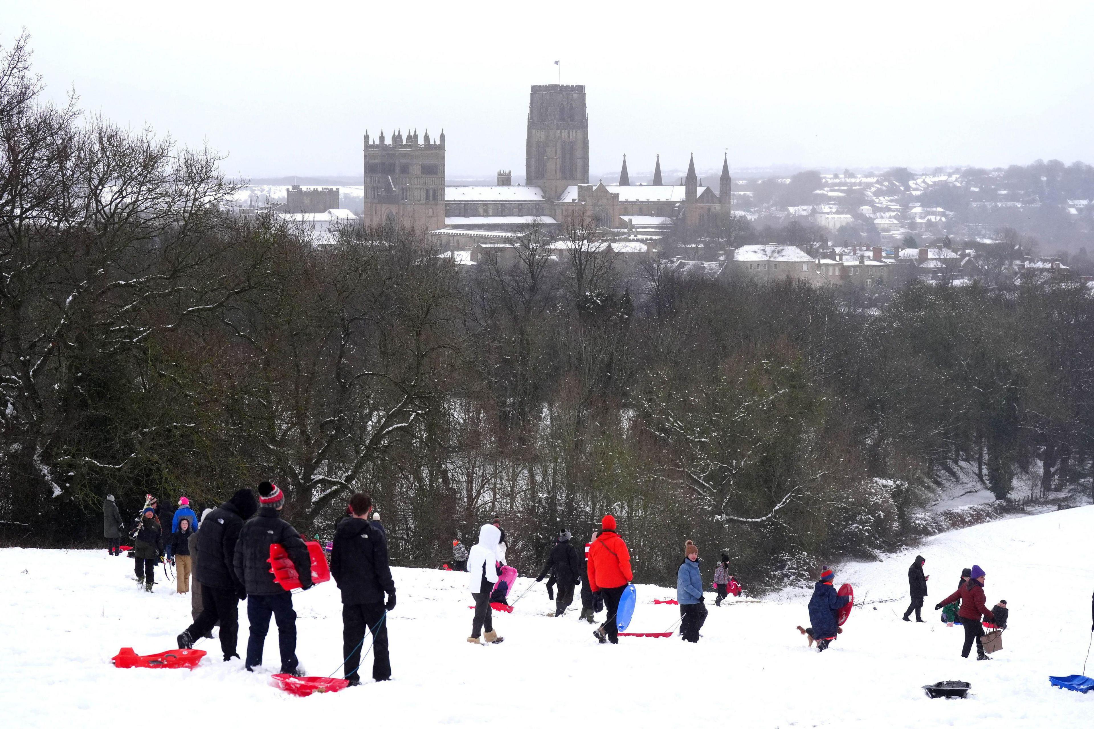 People - who are wrapped up warm - sledging near Durham Cathedral in Durham. 