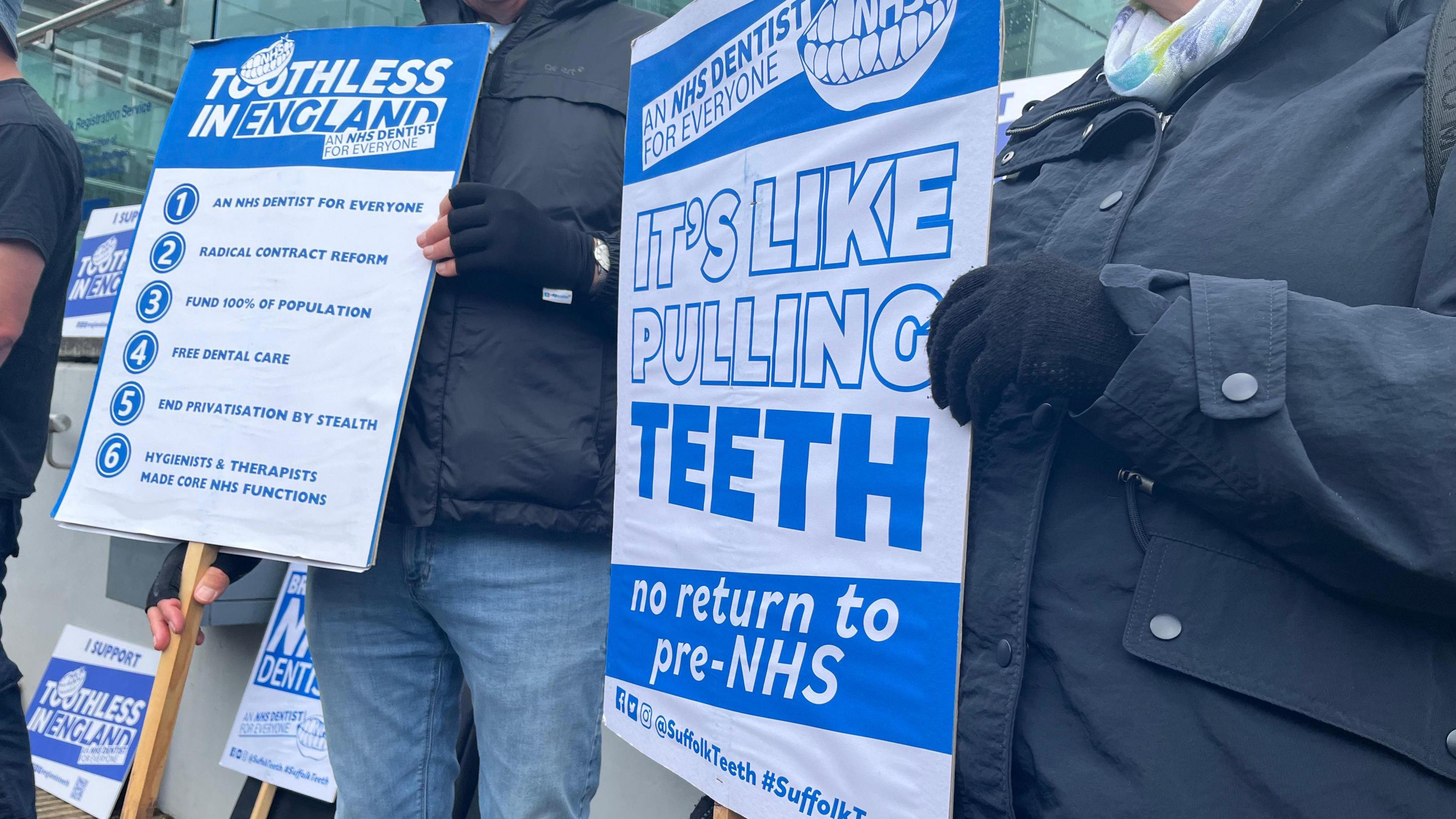 A close-up of one of the campaigner's holding a poster. It reads: "It's like pulling teeth, no return to pre-NHS"