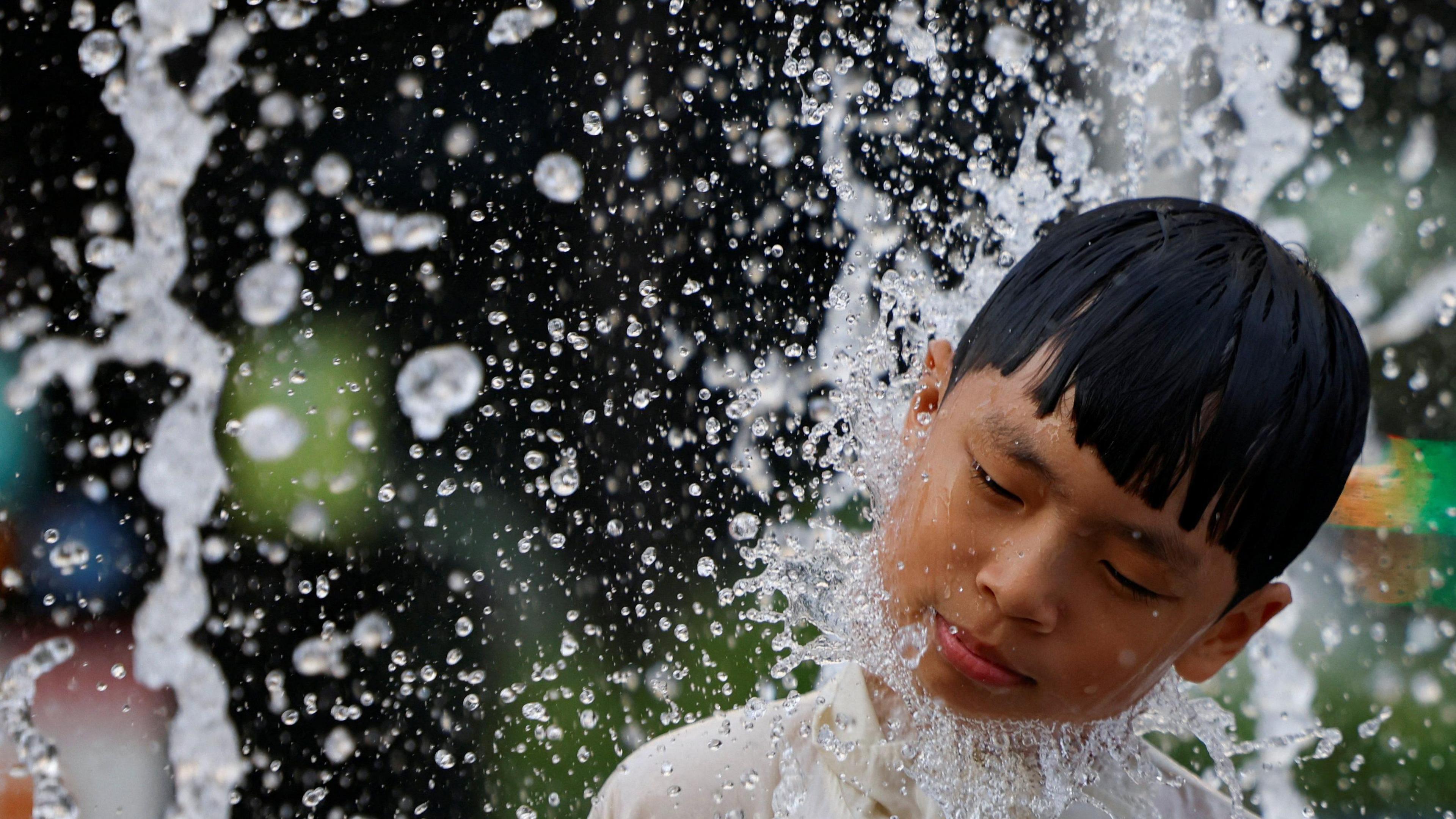 a child with his eyes closed in water sprays.