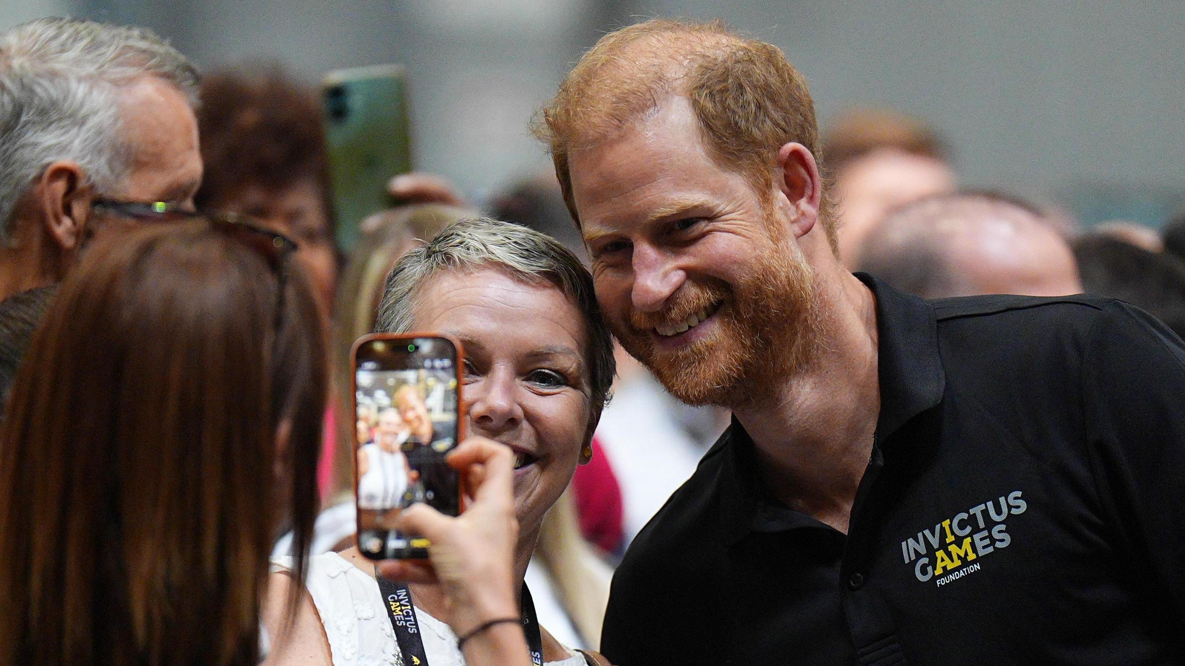 Prince Harry has is photo taken with a woman.