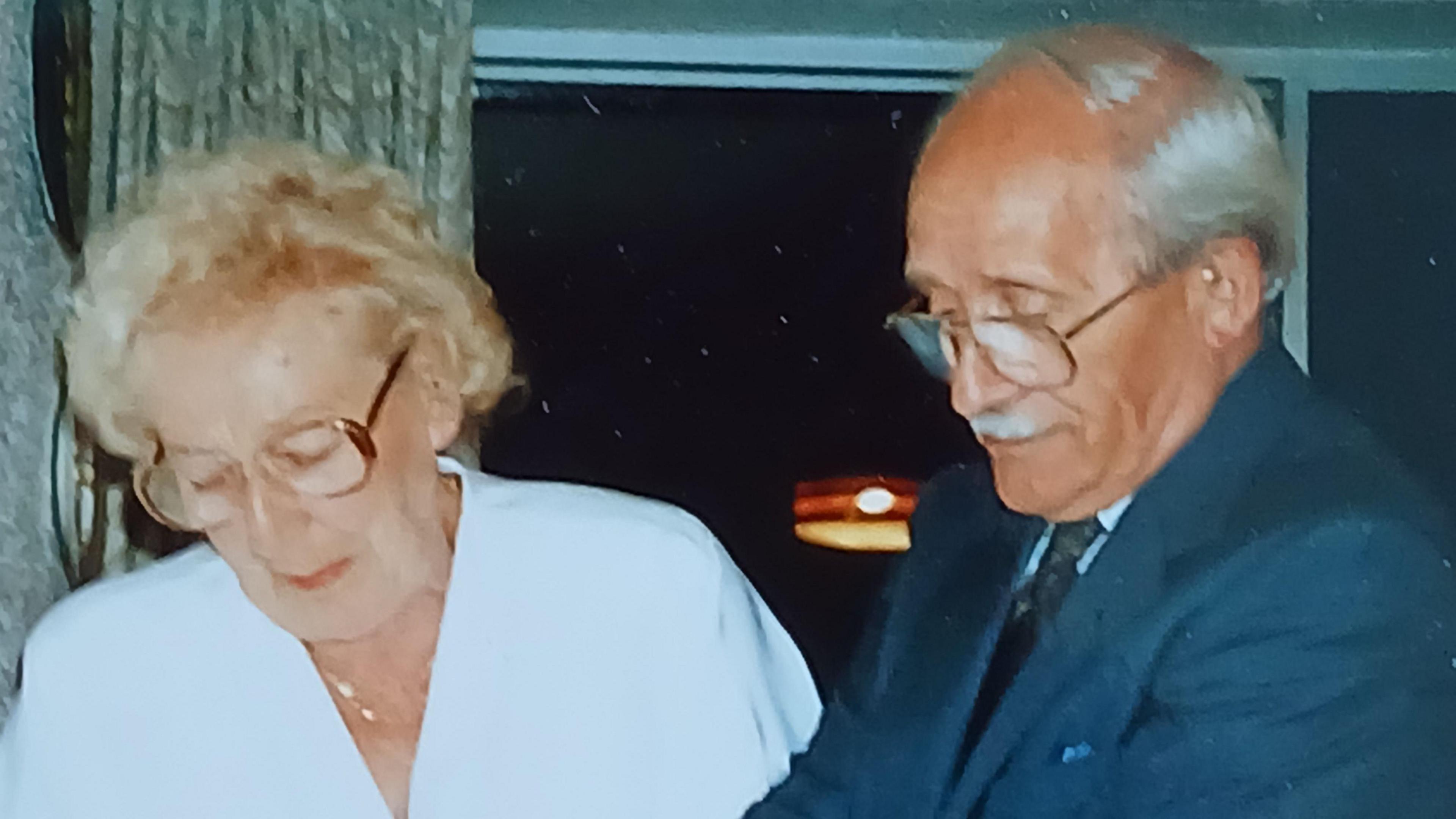 An elderly couple cutting a cake 