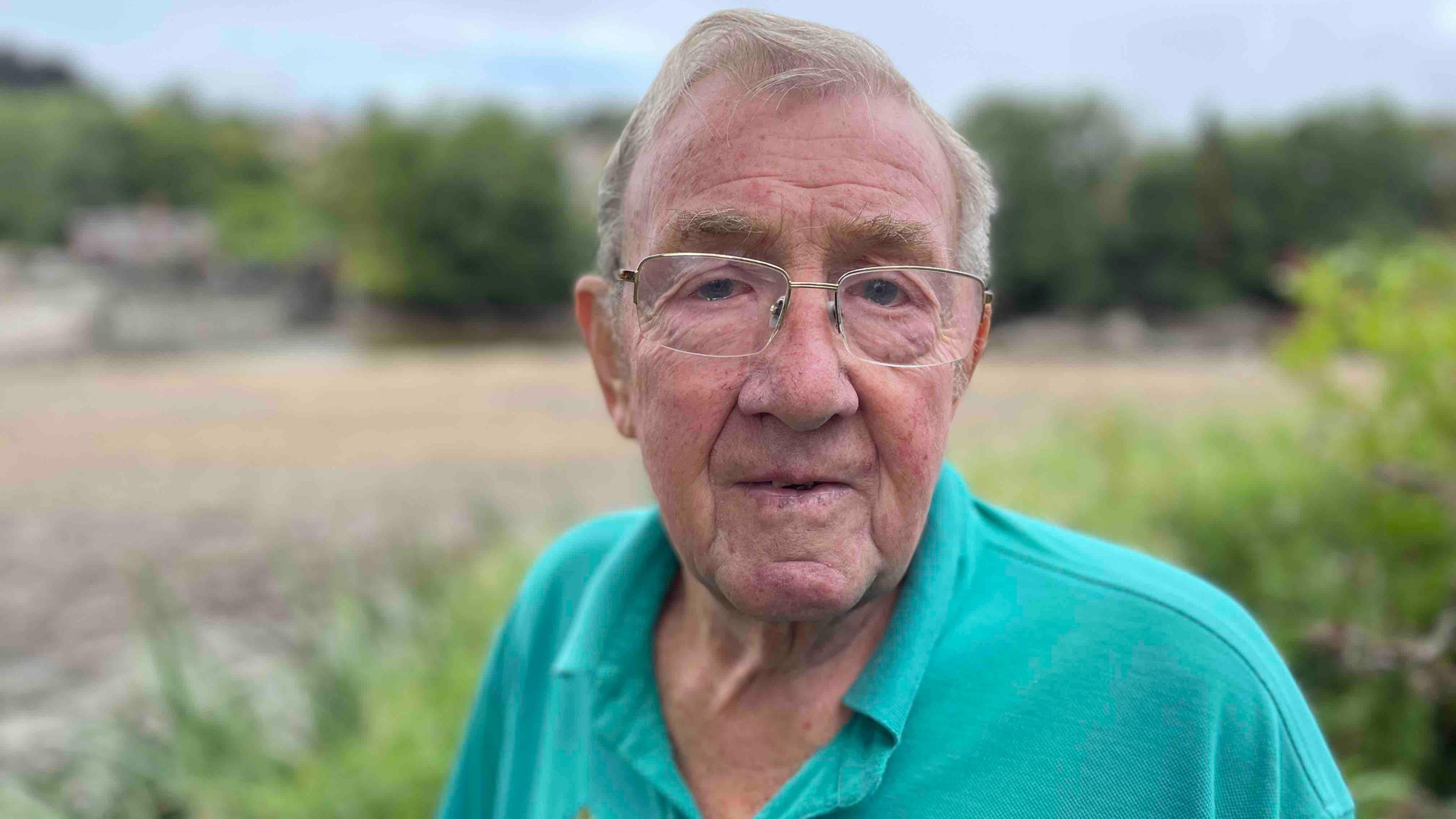 John Nelson from Belper Angling Club looking at the camera. He's wearing glasses and a bright blue Polo top.