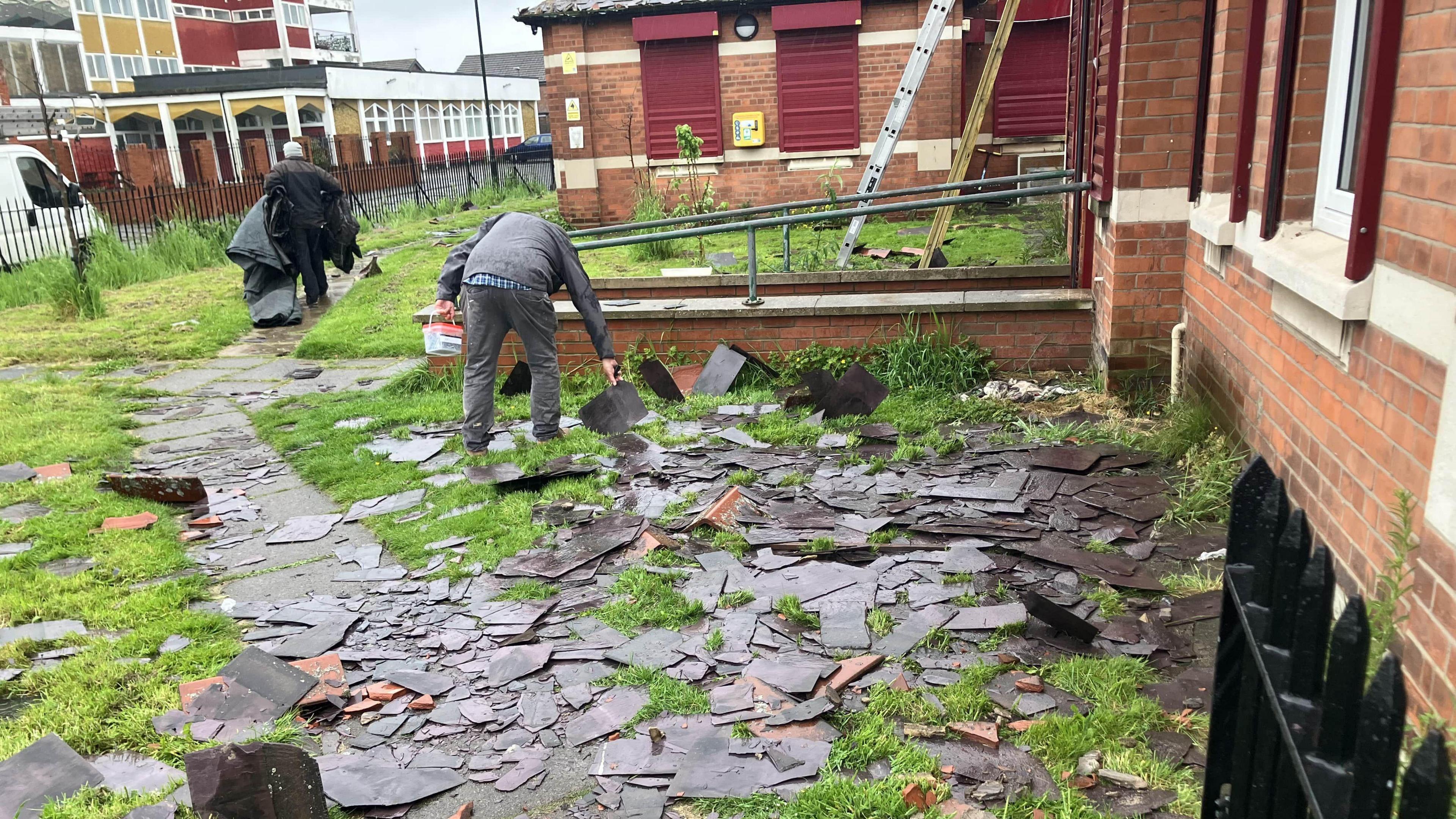 Workers pick up roof tiles and slates after they were thrown off the roof at Harbour Place in Grimsby