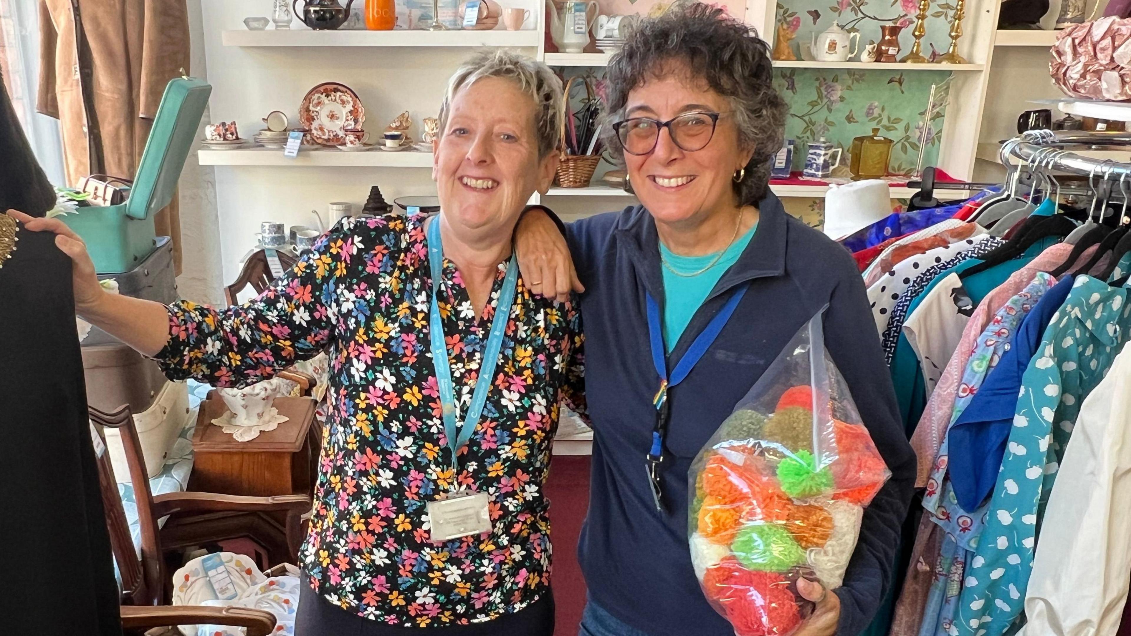 Shop manager Carol Calvert and volunteer Ruth Walsh are standing in amongst the displays at St Leonard's Hospital charity shop in Selby.

They are both smiling at the camera. Ruth is holding a bag of wool and Carol has got her hand on a mannequin. 