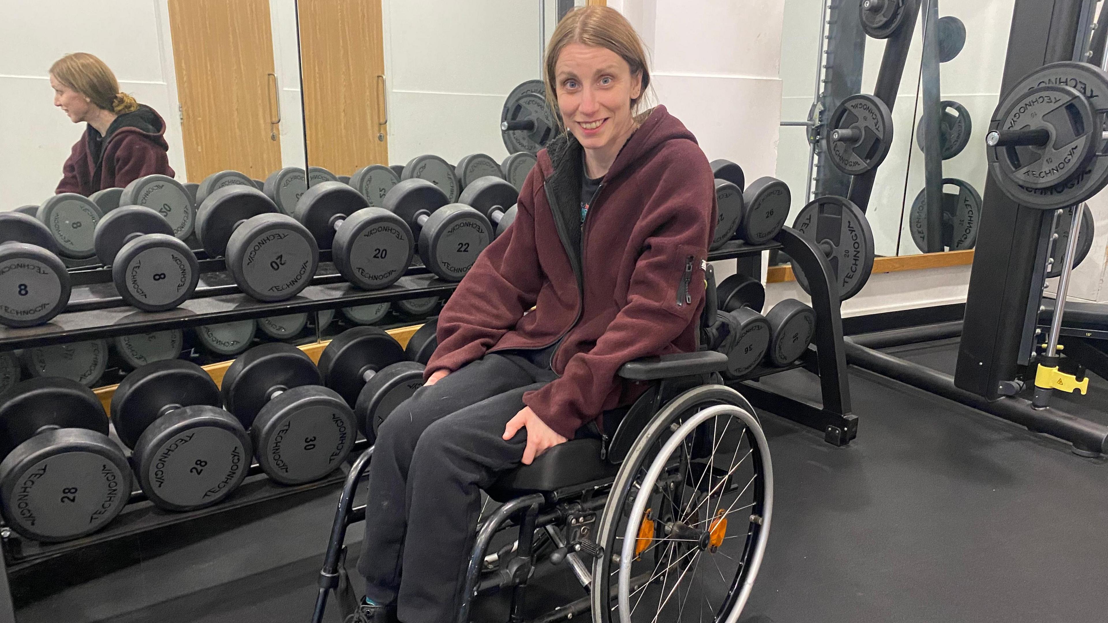 Jos Dent in a wheelchair surrounded by gym equipment