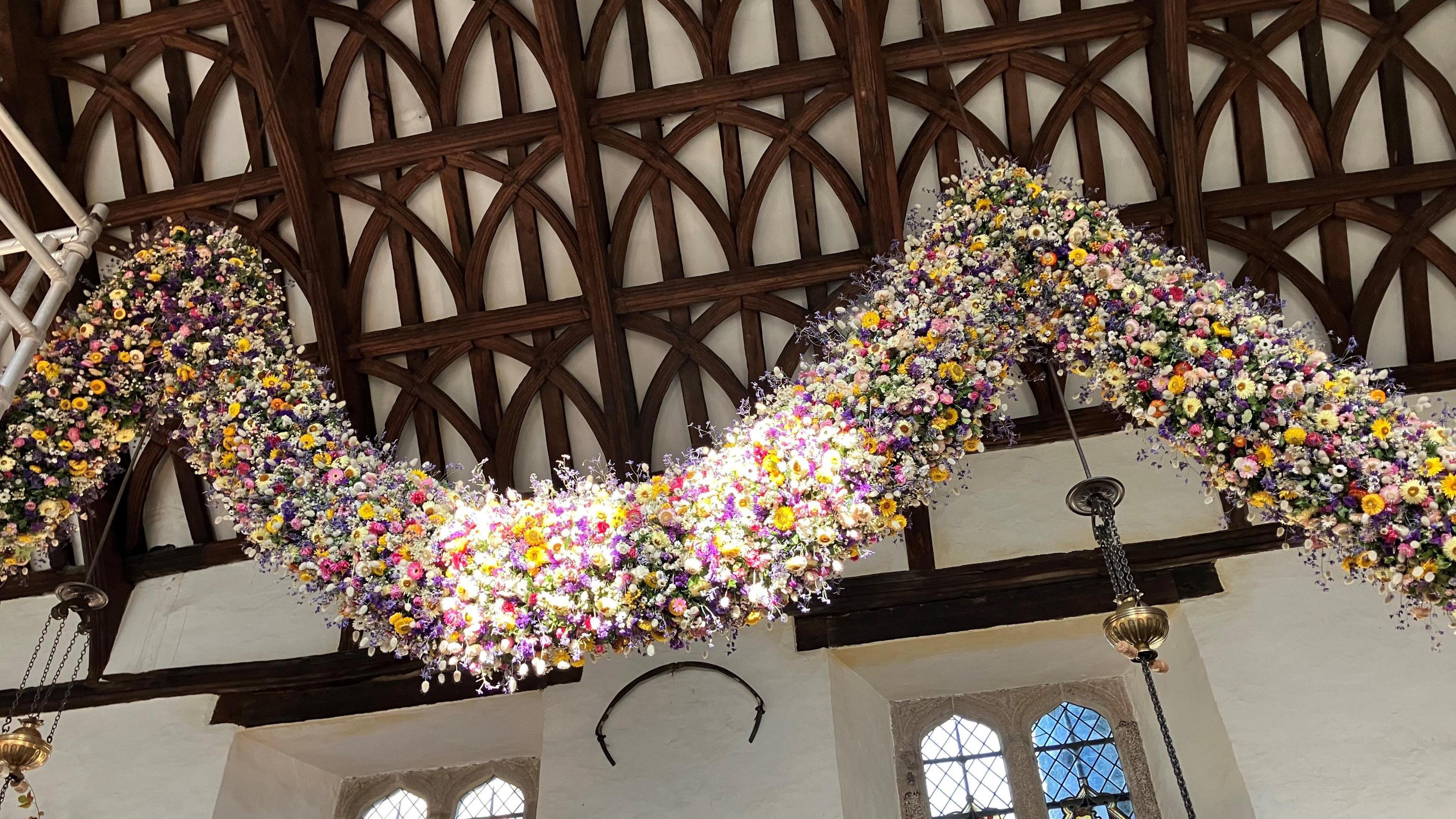 Hanging from the ceiling is a flower garland with striking yellow helichrysums 