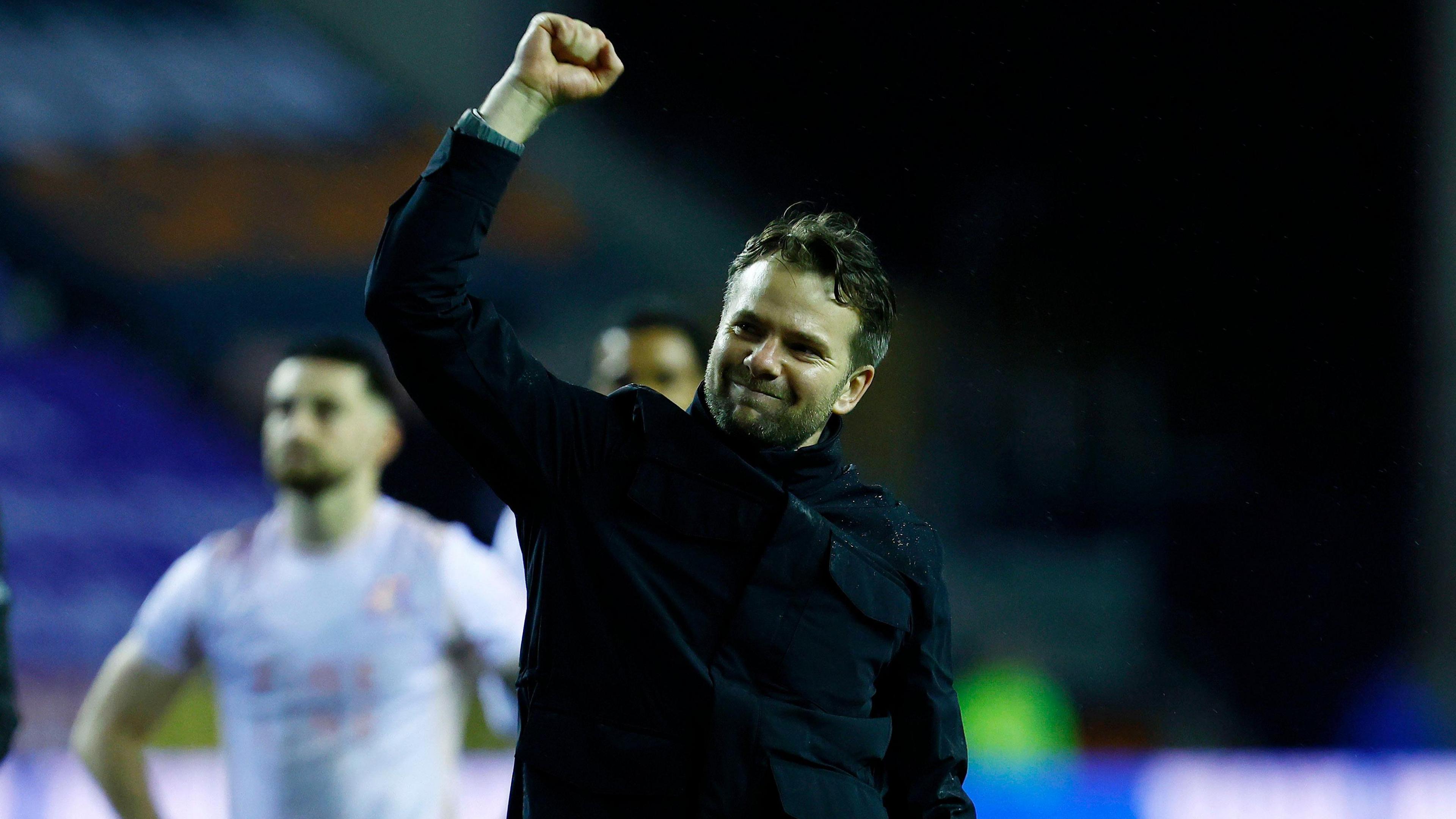 Plymouth Argyle boss Tom Cleverley in the foreground punching the air in celebration after his side's victory at Wigan Athletic while defender Owen Dale stands with hands on hips in the background