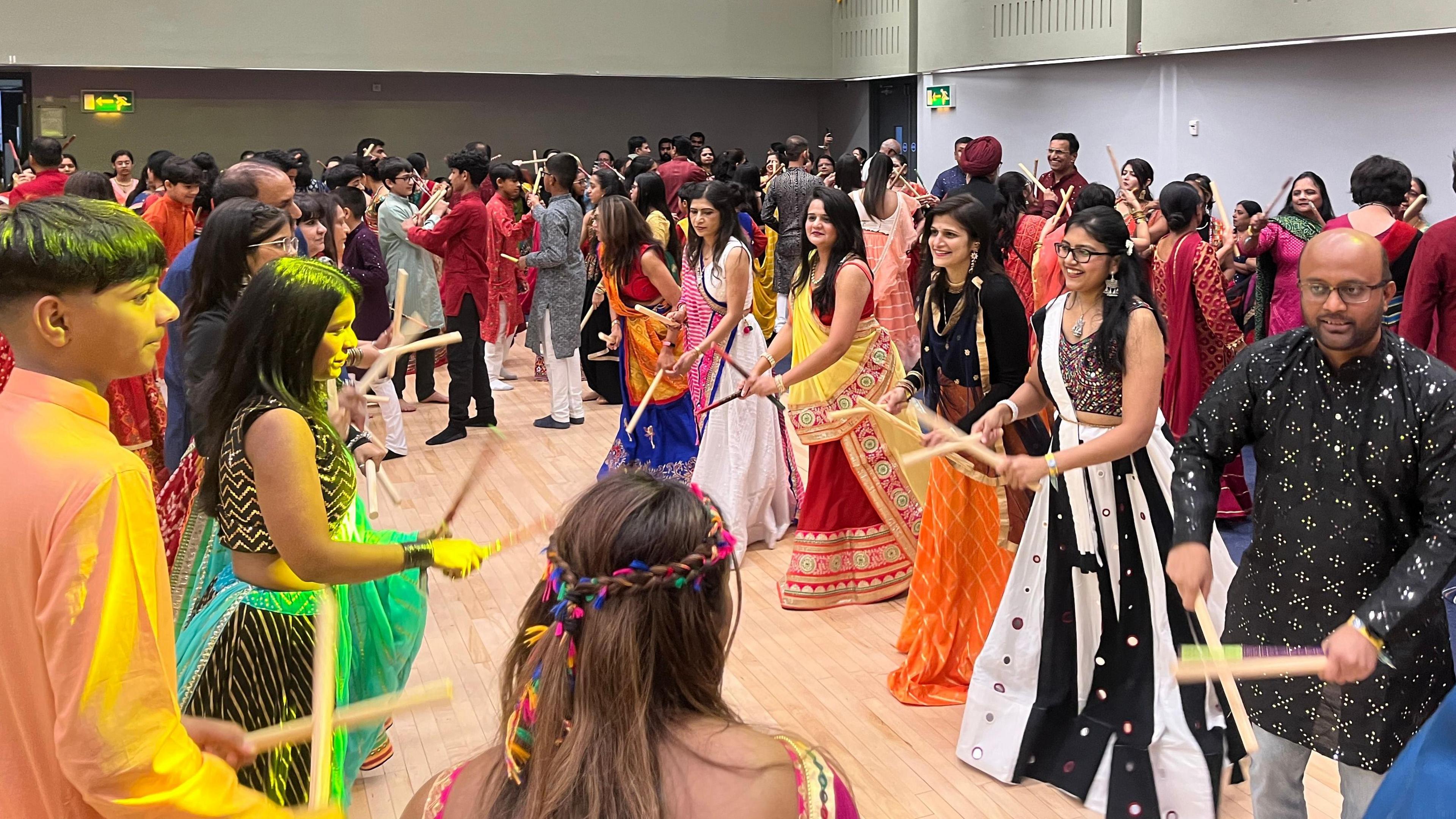 People dressed in traditional Indian clothes to celebrate Navratri dancing with dandiya sticks 