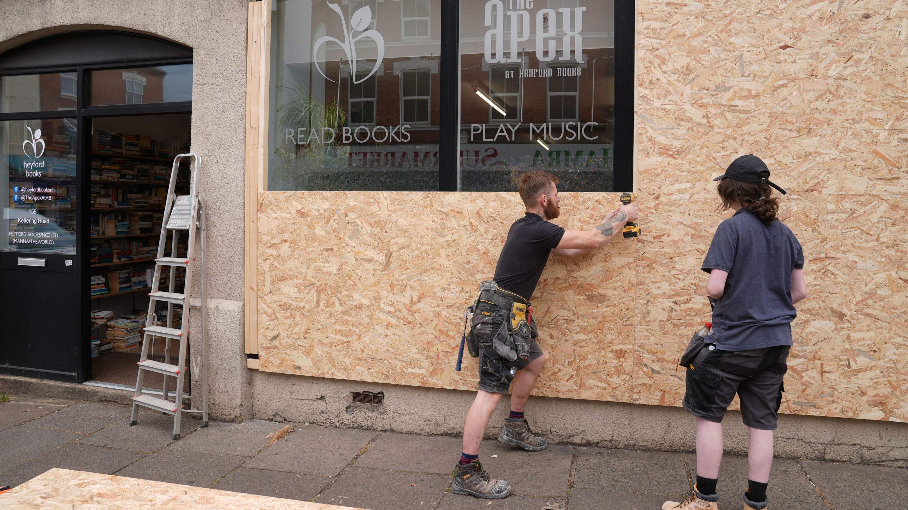 Two men boarding up a shop window