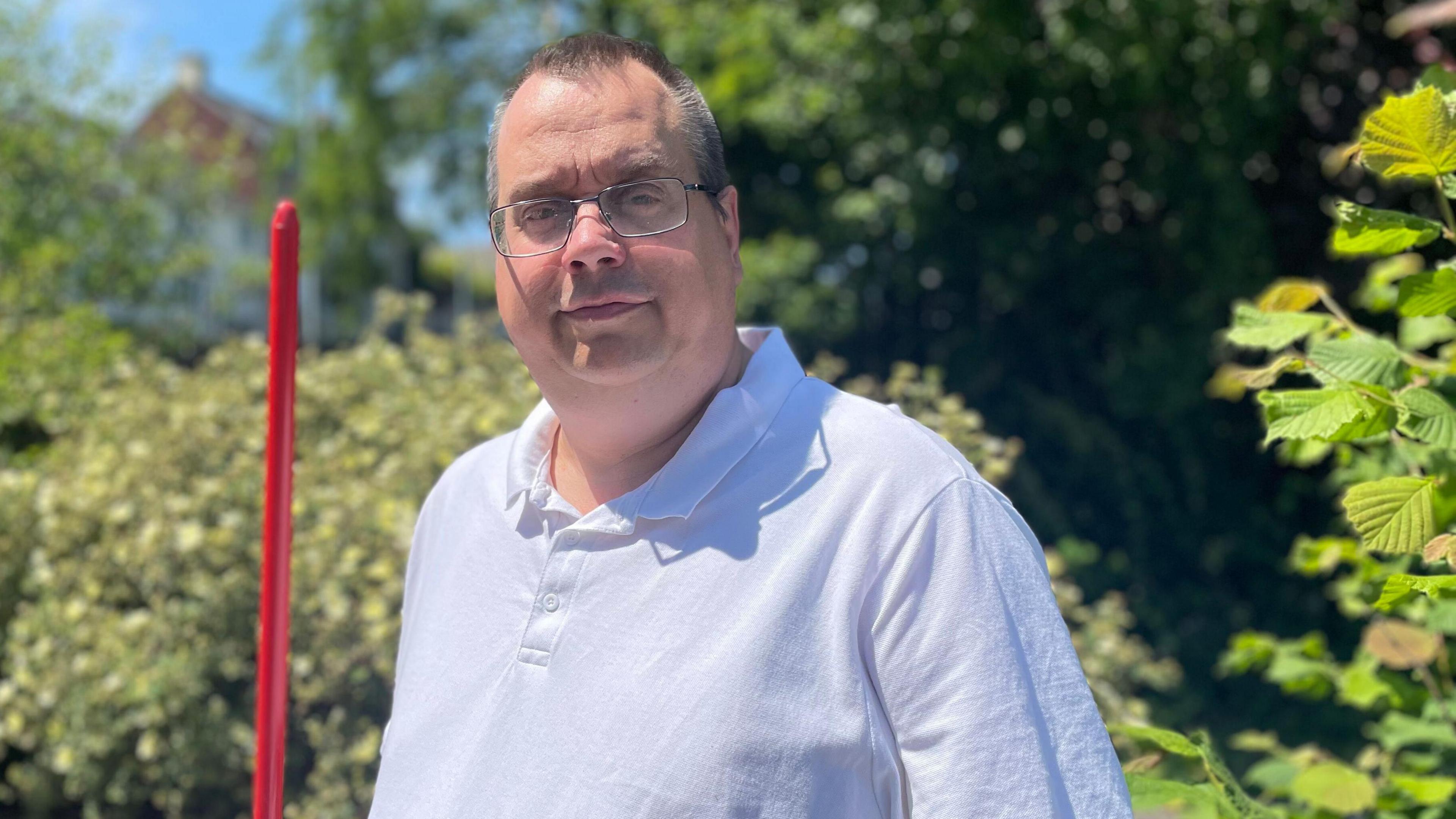 A man in a blue shirt smiles for the camera in the sunshine