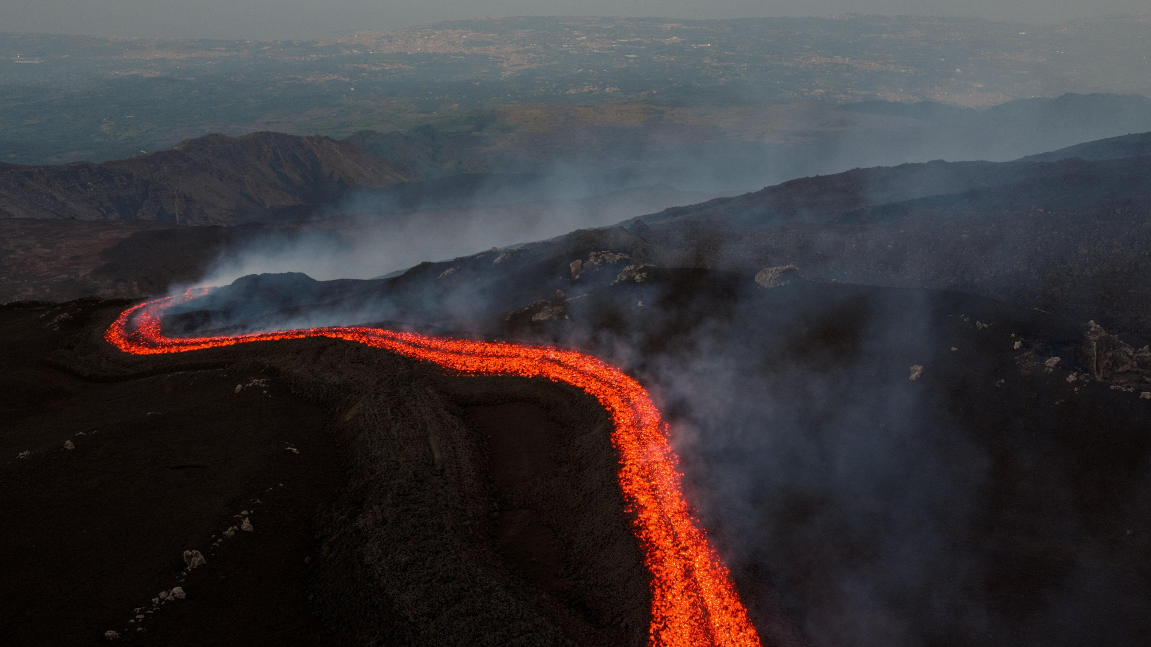 A drone picture shows a stream of molten lava flowing down the slope of Mount Etna.