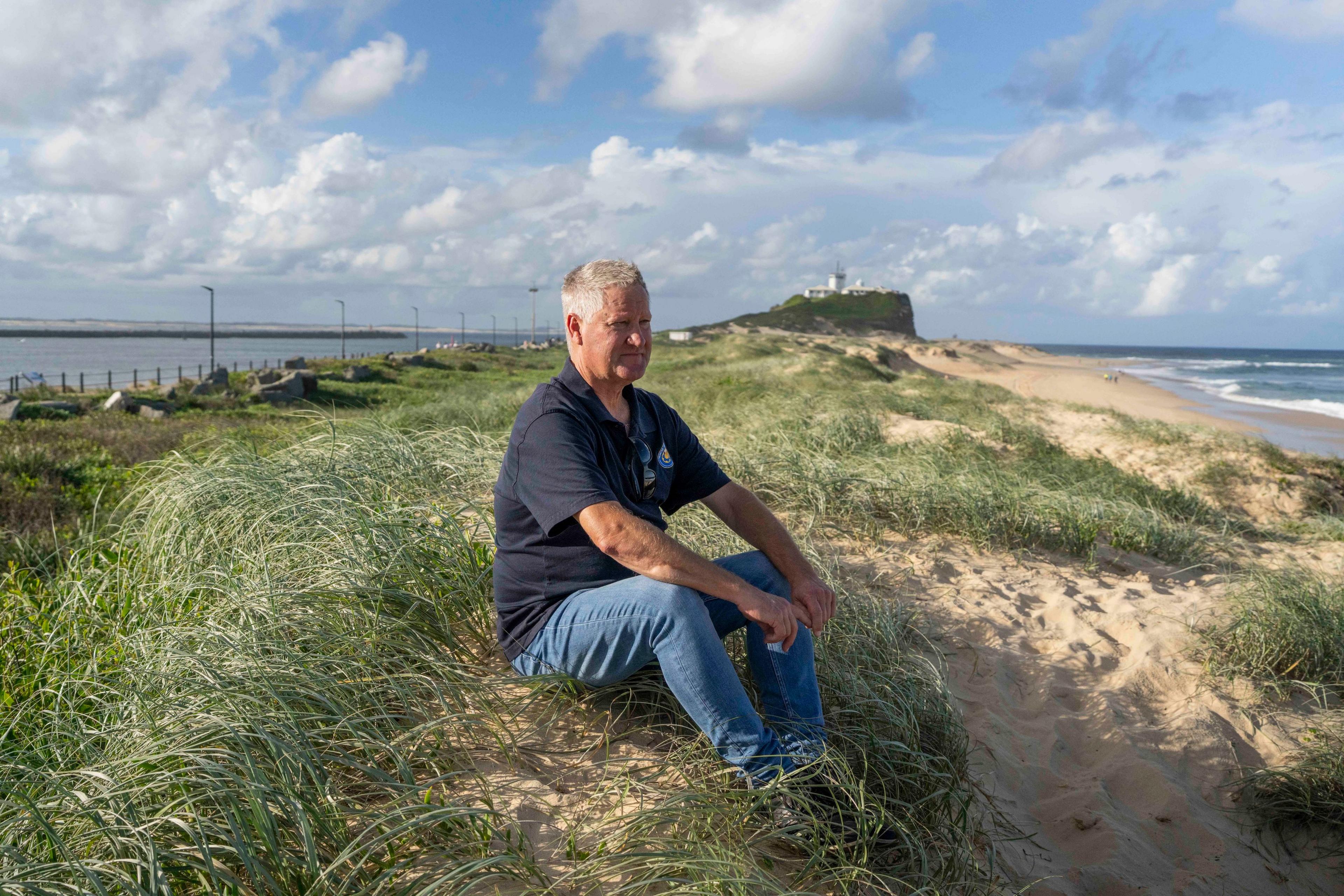 Hunter Jobs Alliance coordinator Justin Page, sits on the dunes at Newcastle Beach
