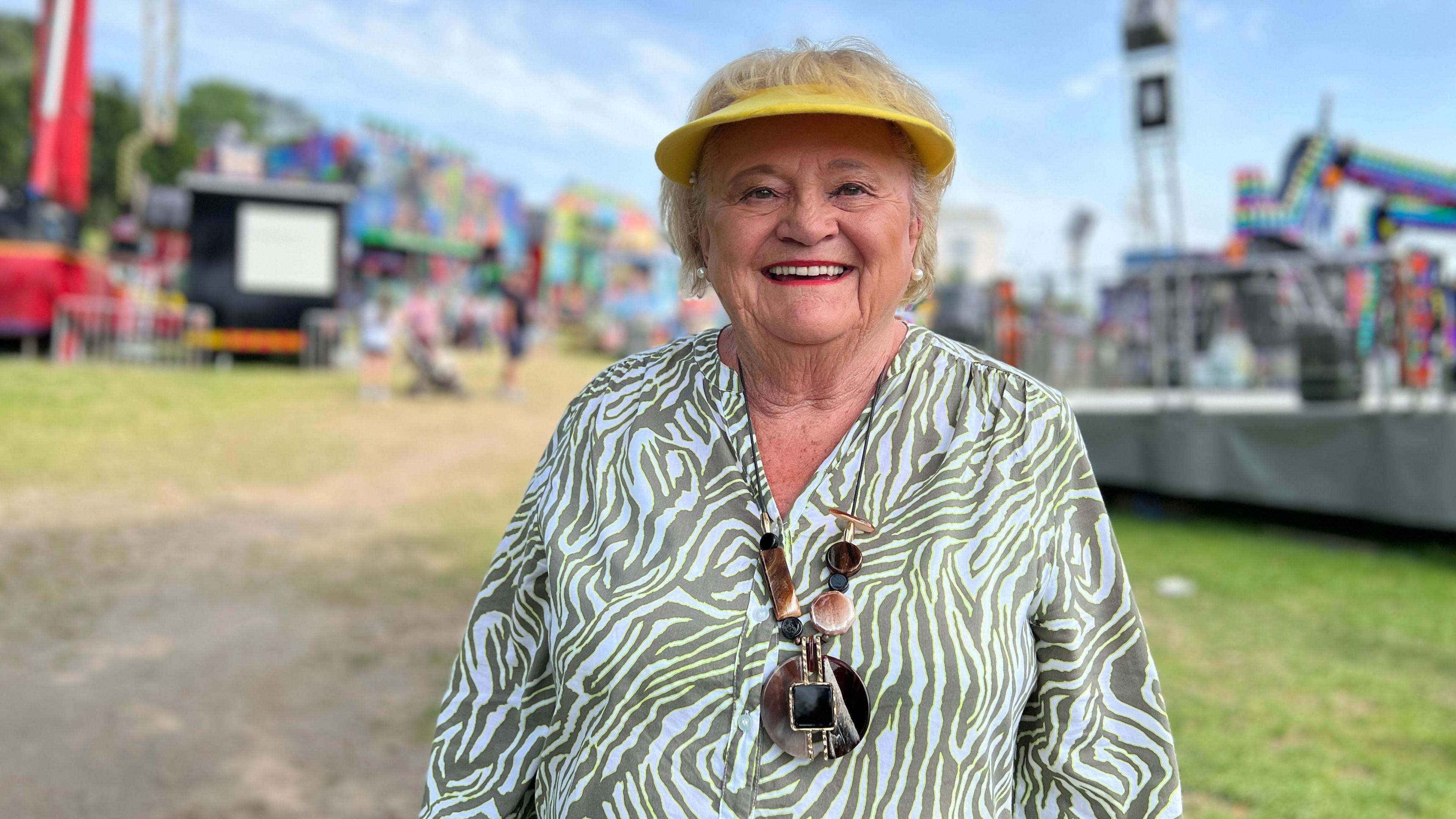 Jeanette smiles at the camera with the funfair behind her