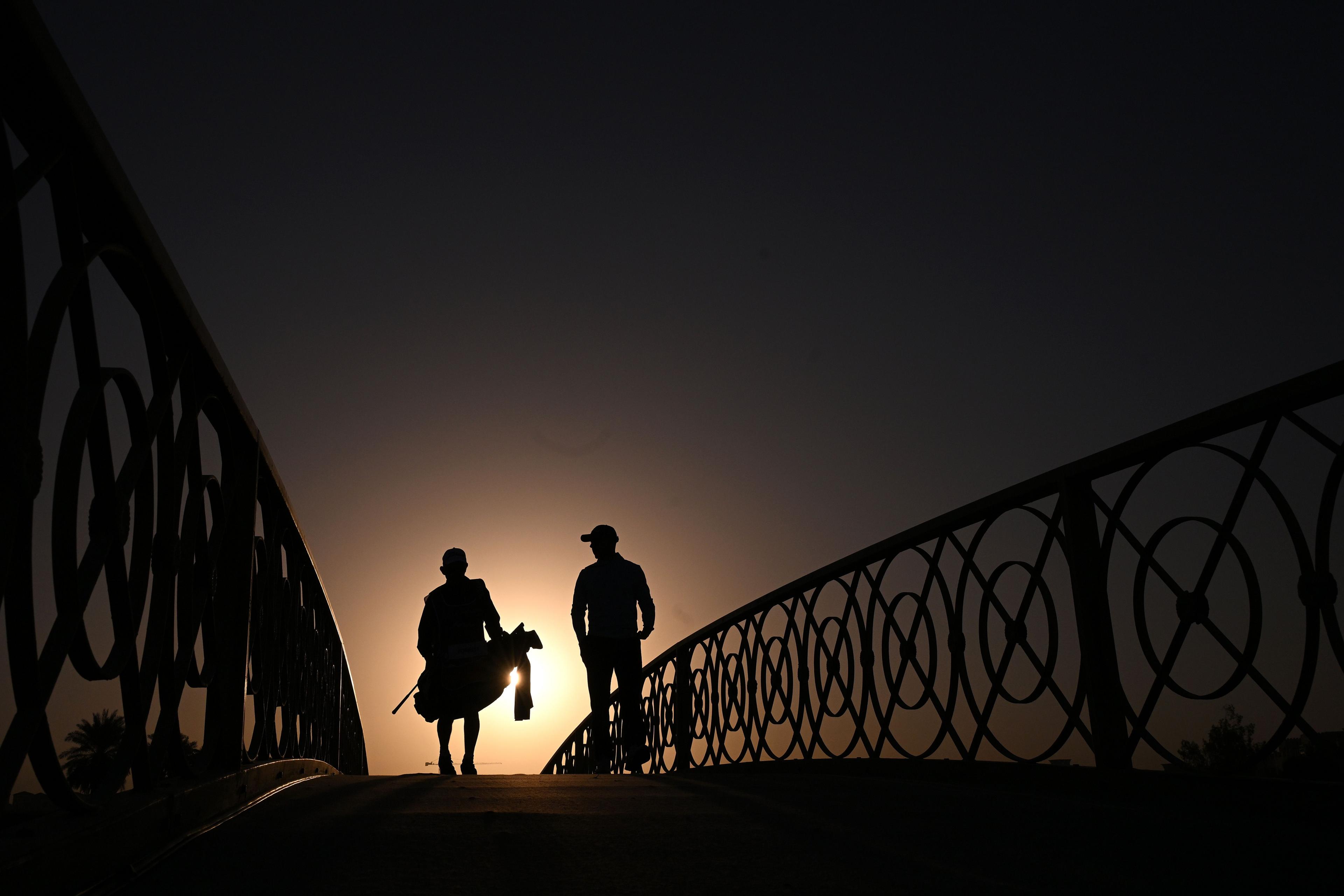 Grant Forrest of Scotland (R) walks with his caddie, David Kenny (L) over a bridge to the 10th hole on day one of the Ras Al Khaimah Championship 2025 at Al Hamra Golf Club in Ras al Khaimah, United Arab Emirates