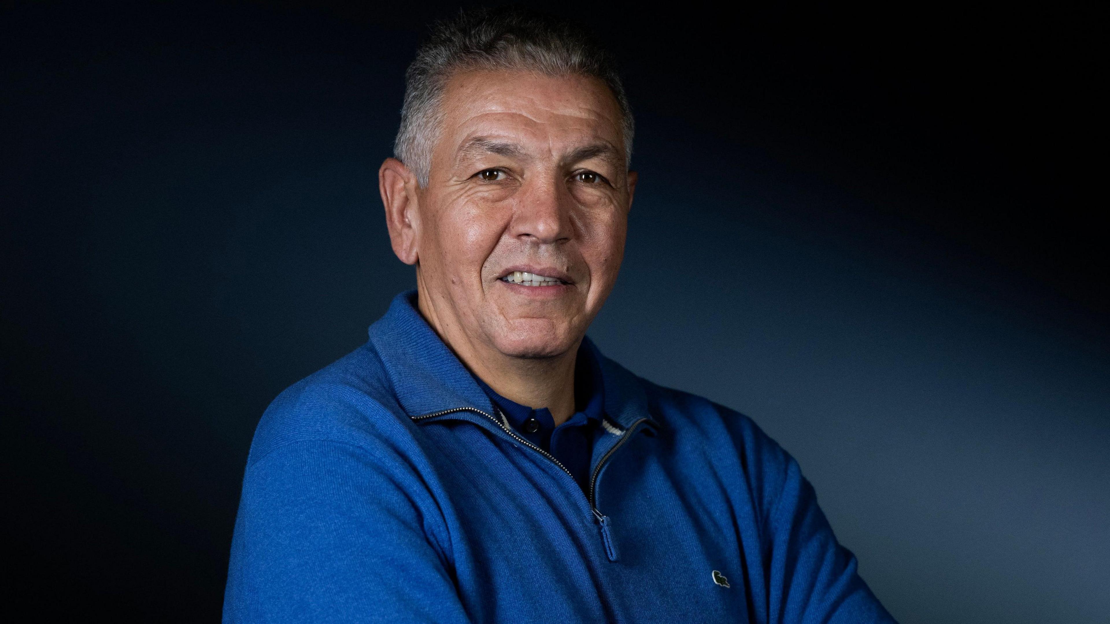 A headshot of Abdelatif Benazzi wearing a royal blue zip-up fleece