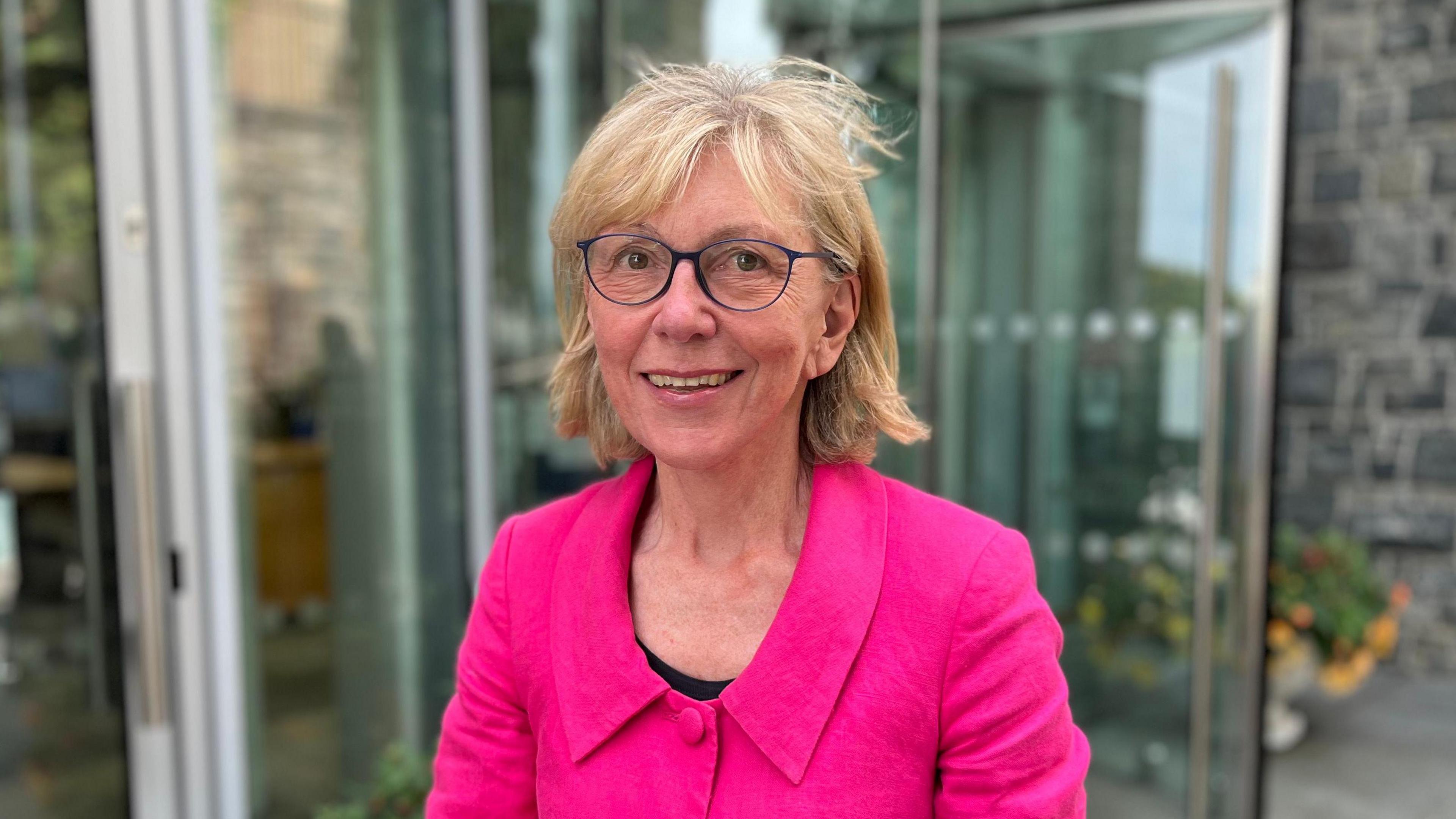 Deputy Yvonne Burford, who has short blonde hair, blue rimmed glasses and is wearing a pink jacket.