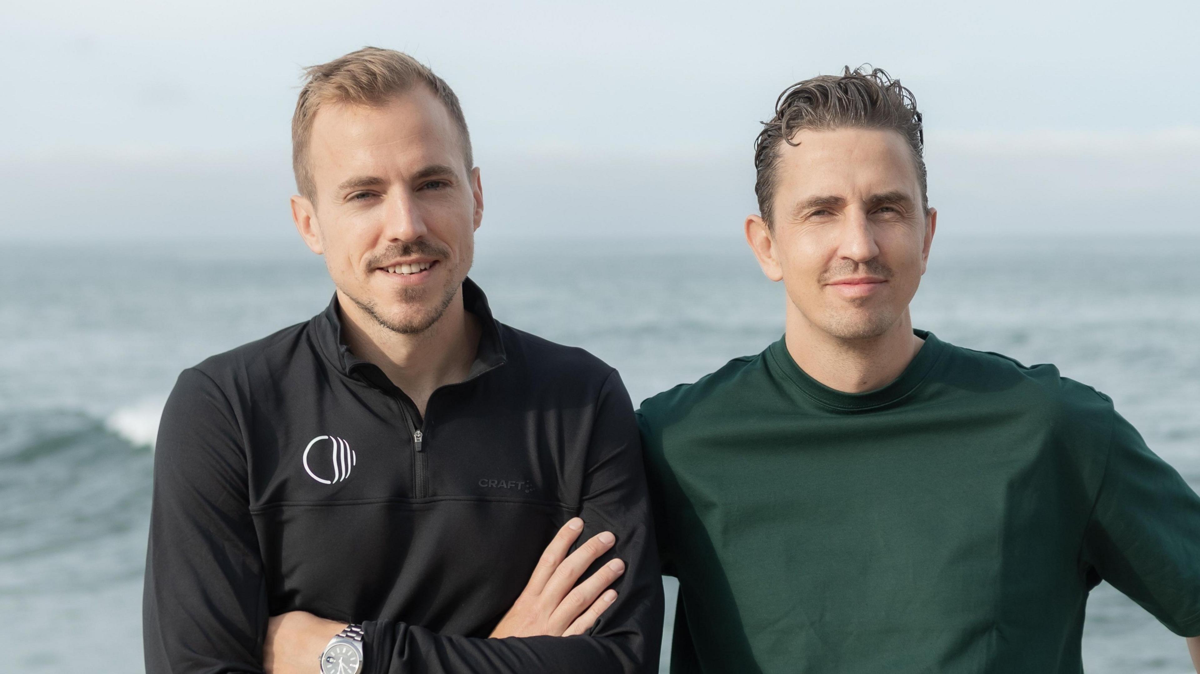 Corti co-founders Lars Maaloe (left) and Andreas Cleve stand together with the sea behind them.