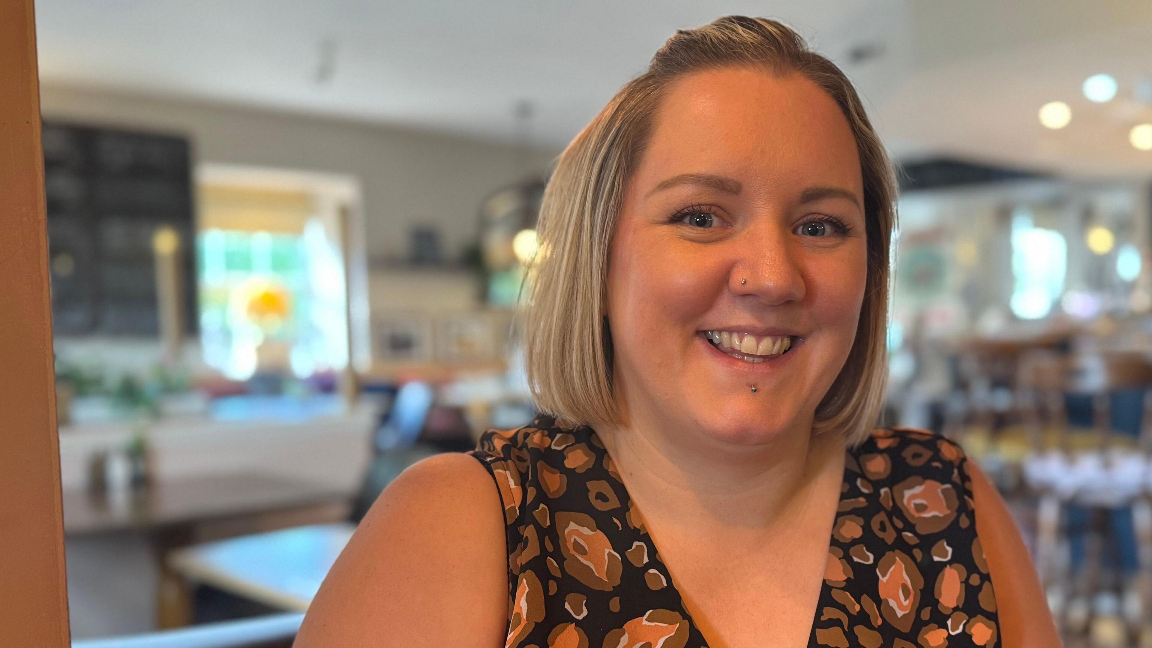 The head and shoulders of Elle Snelling. She is smiling and looking directly into the camera. She appears to be sitting in the pub, with bar stools behind her.