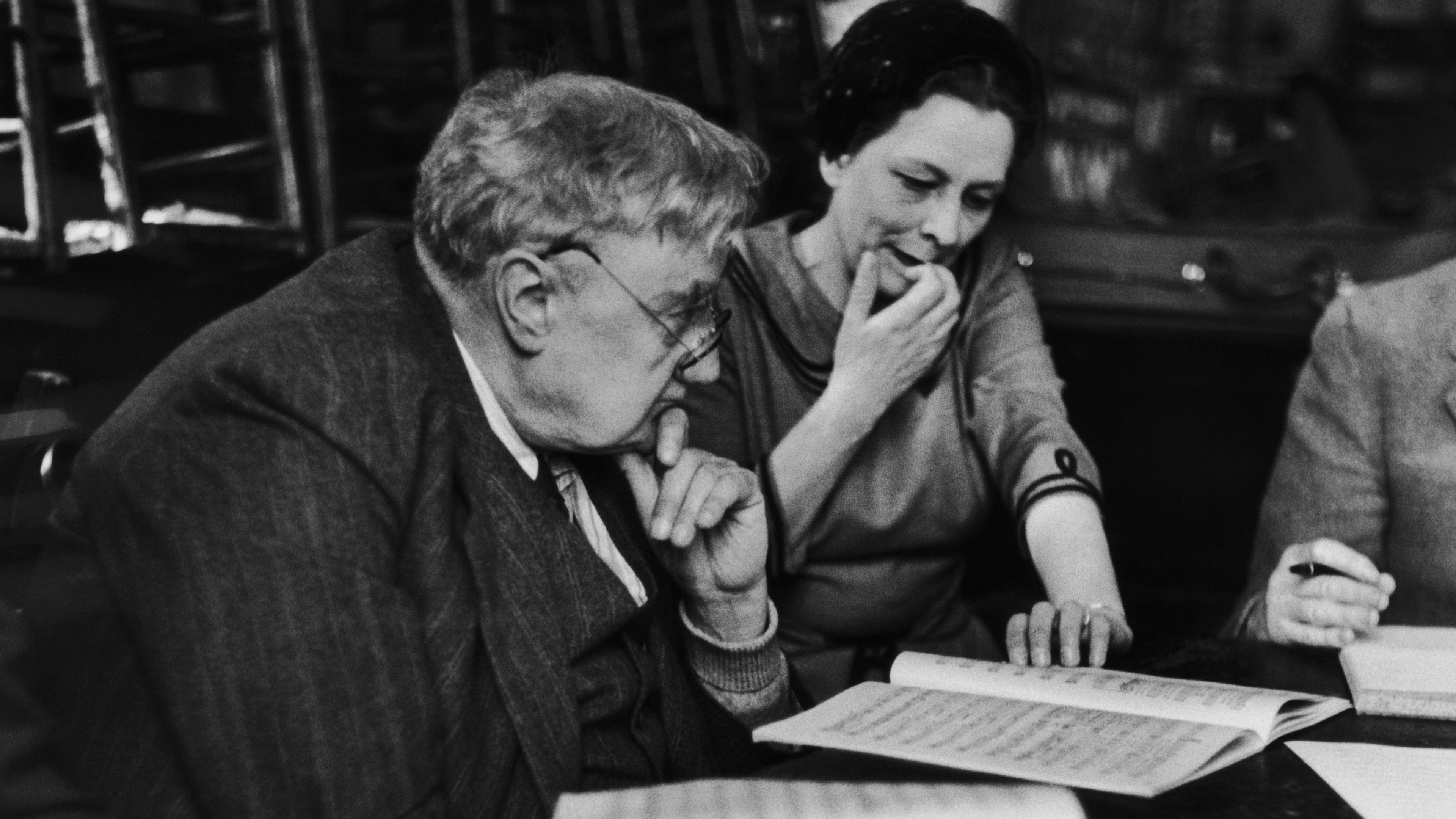 Black and white image of an elderly Ralph Vaughan Willilams looking at sheet music with a woman sat next to him