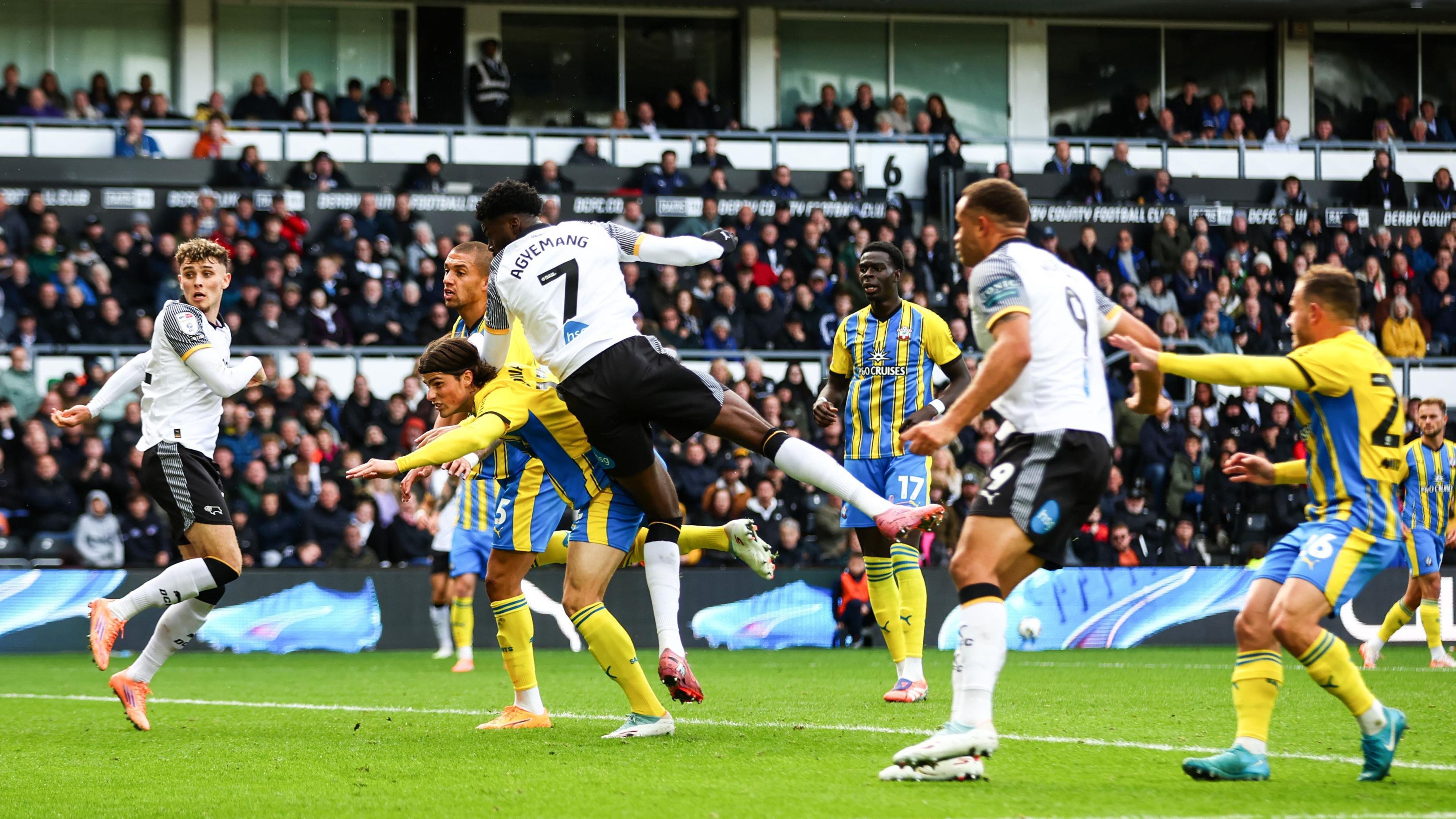 Patrick Agyemang heads the ball (out of shot) with other players watching on