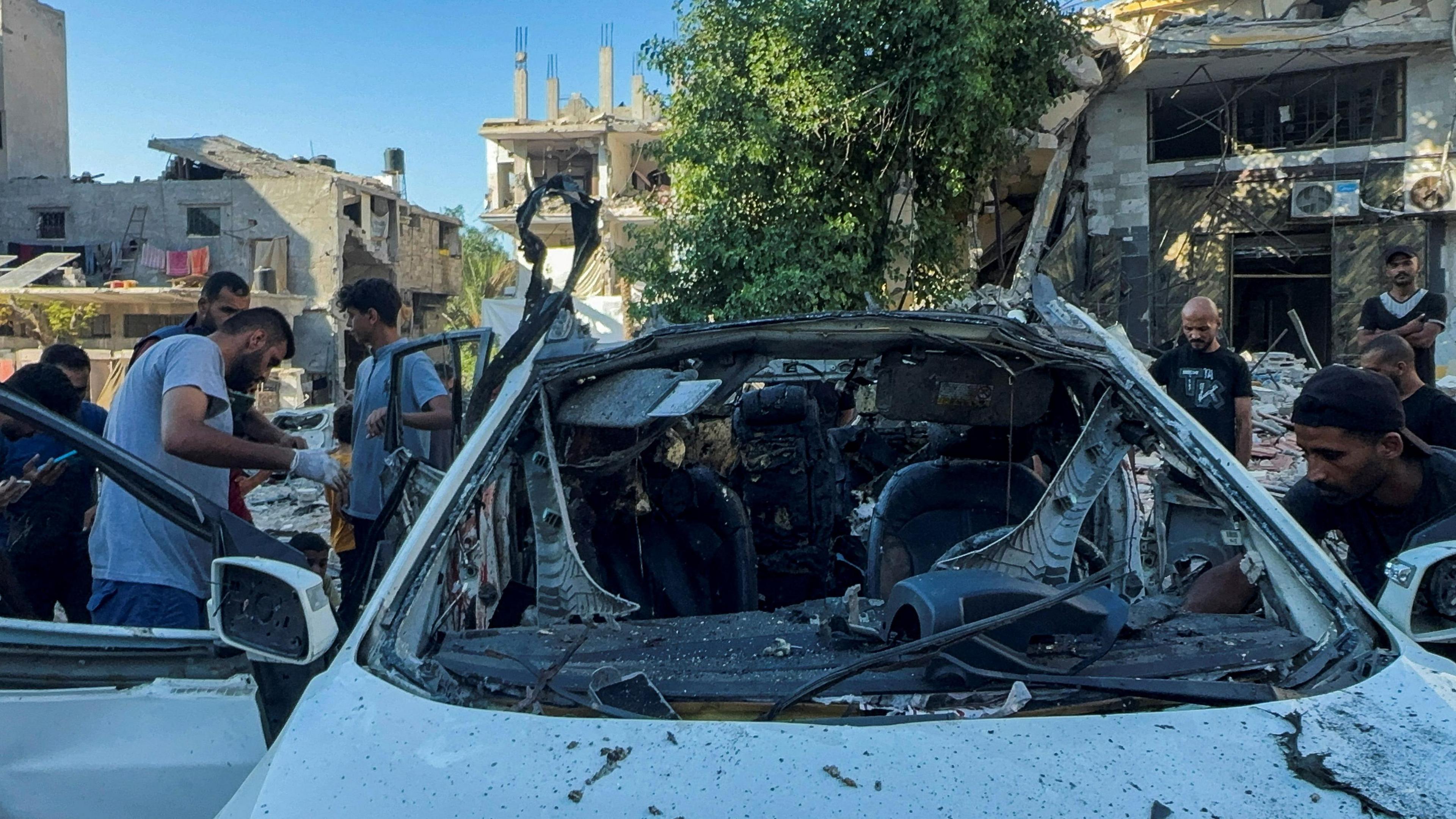 Palestinians inspect a vehicle where Al Jazeera said its reporter Ismail al-Ghoul and cameraman Ramy al-Rifi were killed in an Israeli strike in Gaza City.